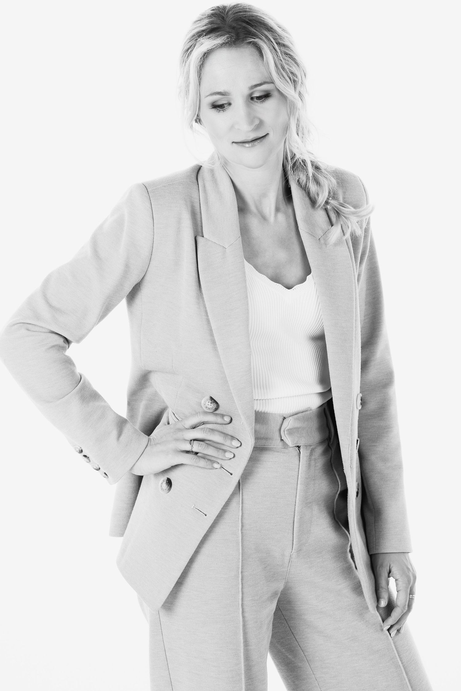 Studio fashion portrait showing a light colored pantsuit styled with a white top.