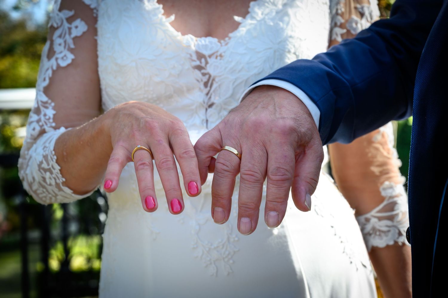 Close-up of hands with wedding rings during an outdoor ceremony.