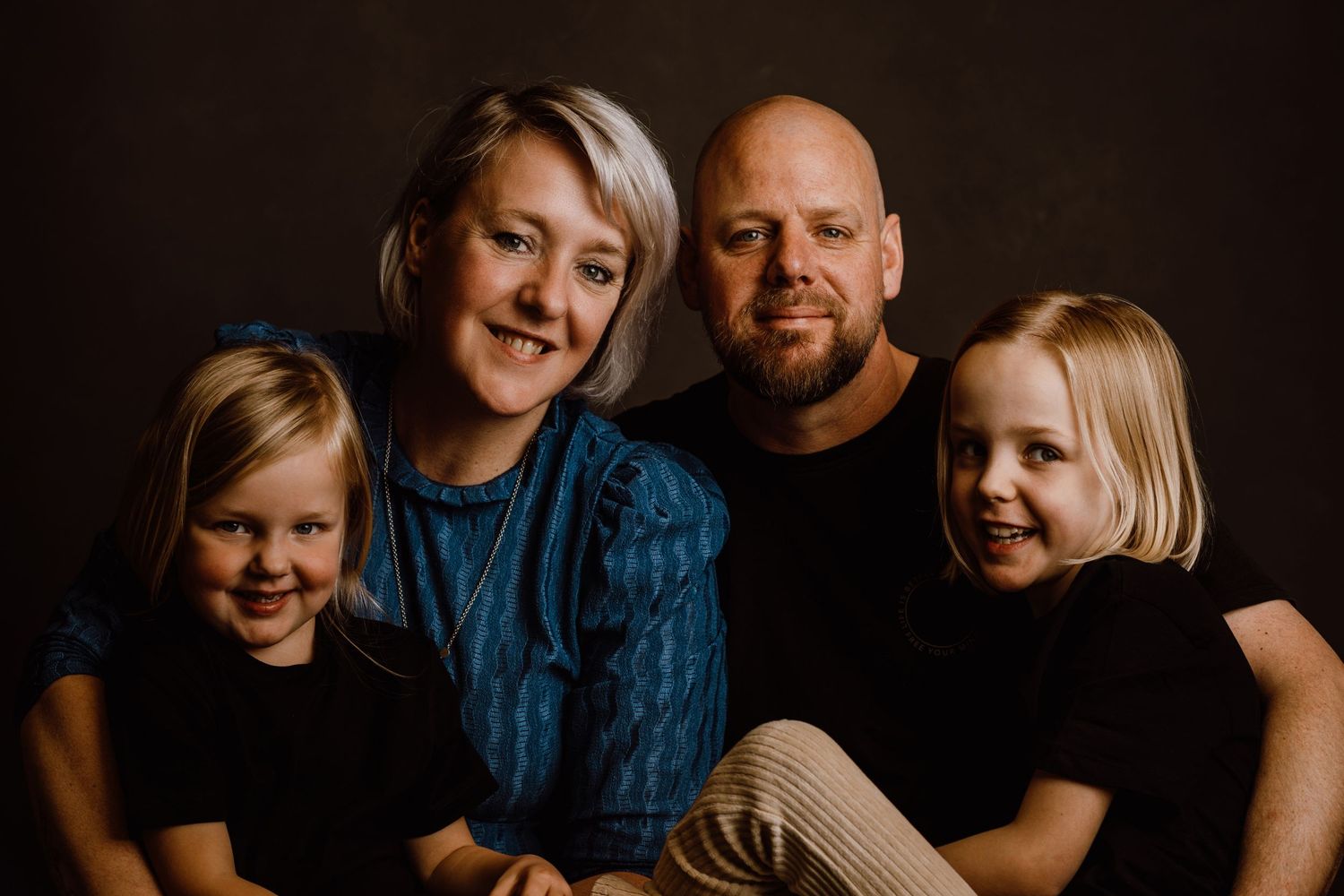Family portrait series with dark background showing casual poses and genuine smiles.