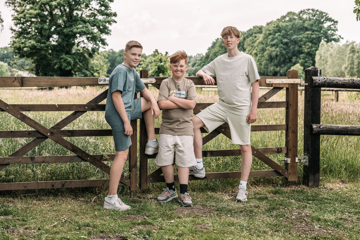 Relaxed outdoor family portraits by wooden fence in countryside setting.