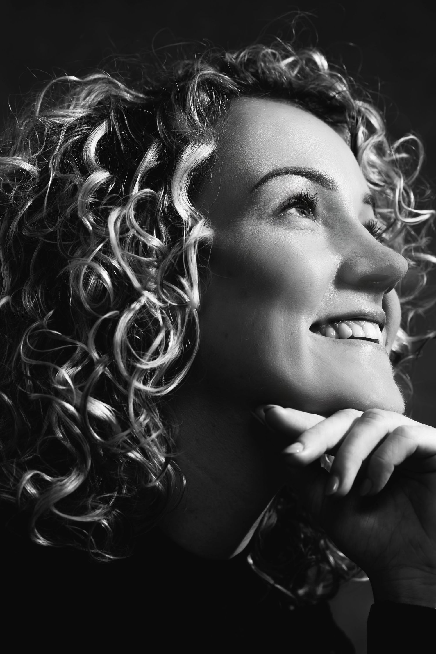 Dramatic black and white profile shot showcasing defined curls and a contemplative expression.