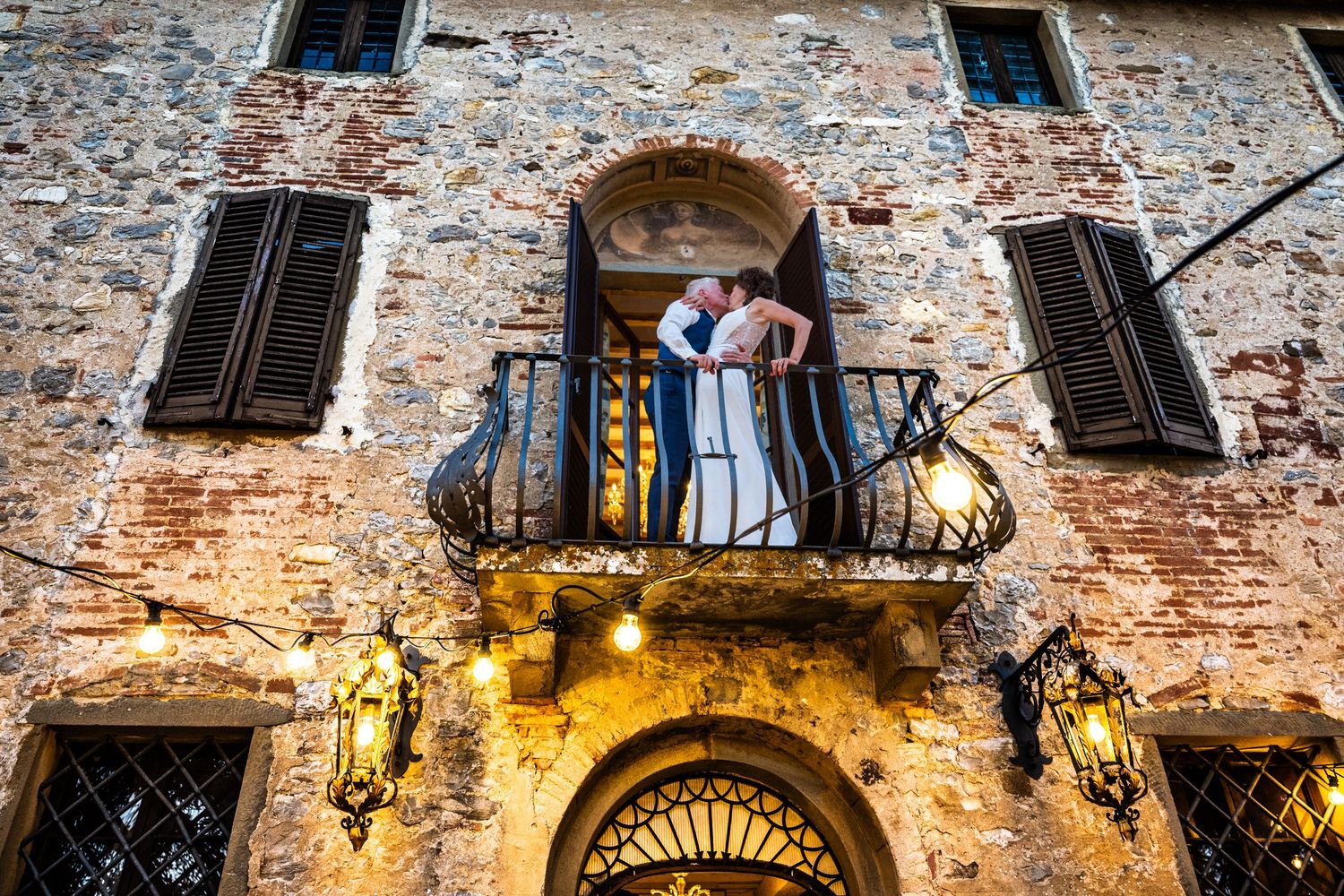 Romantic moment captured on rustic Italian balcony of stone building.