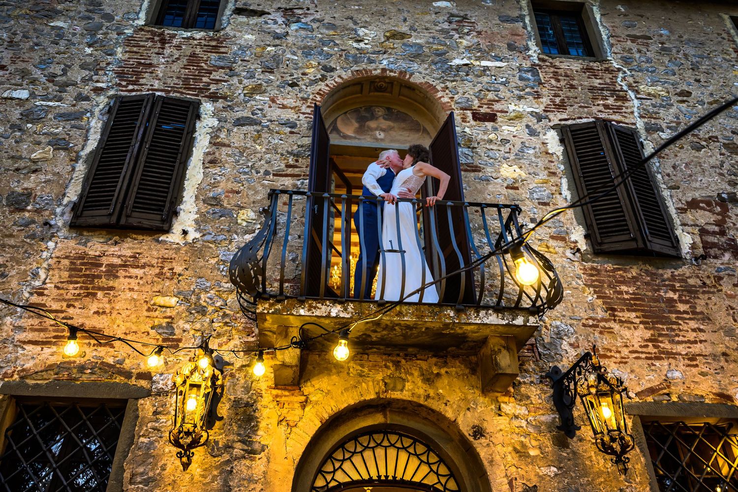 Medieval stone building exterior with illuminated balconies and traditional shuttered windows.