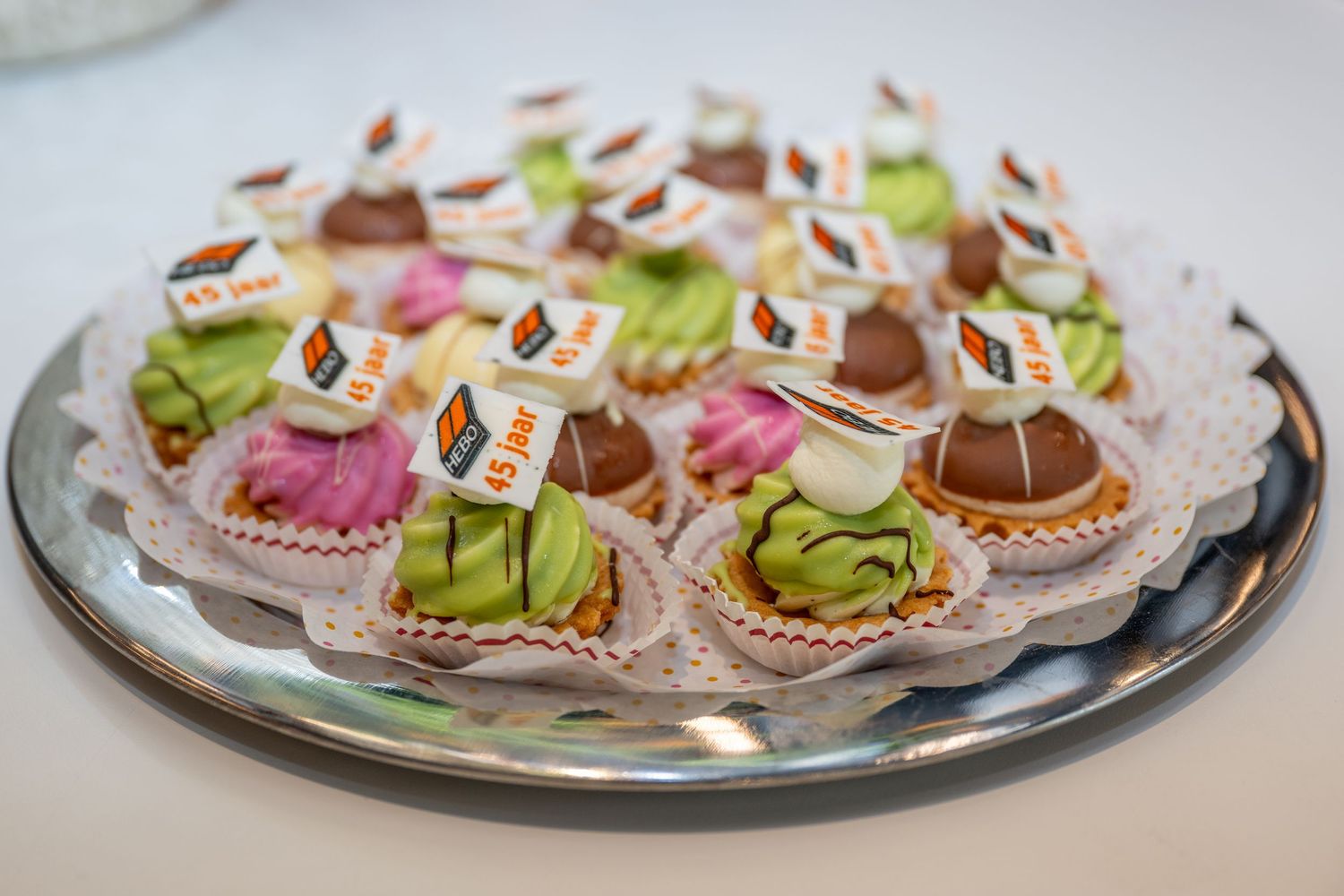 Colorful assortment of miniature pastries and desserts arranged on silver serving platters.