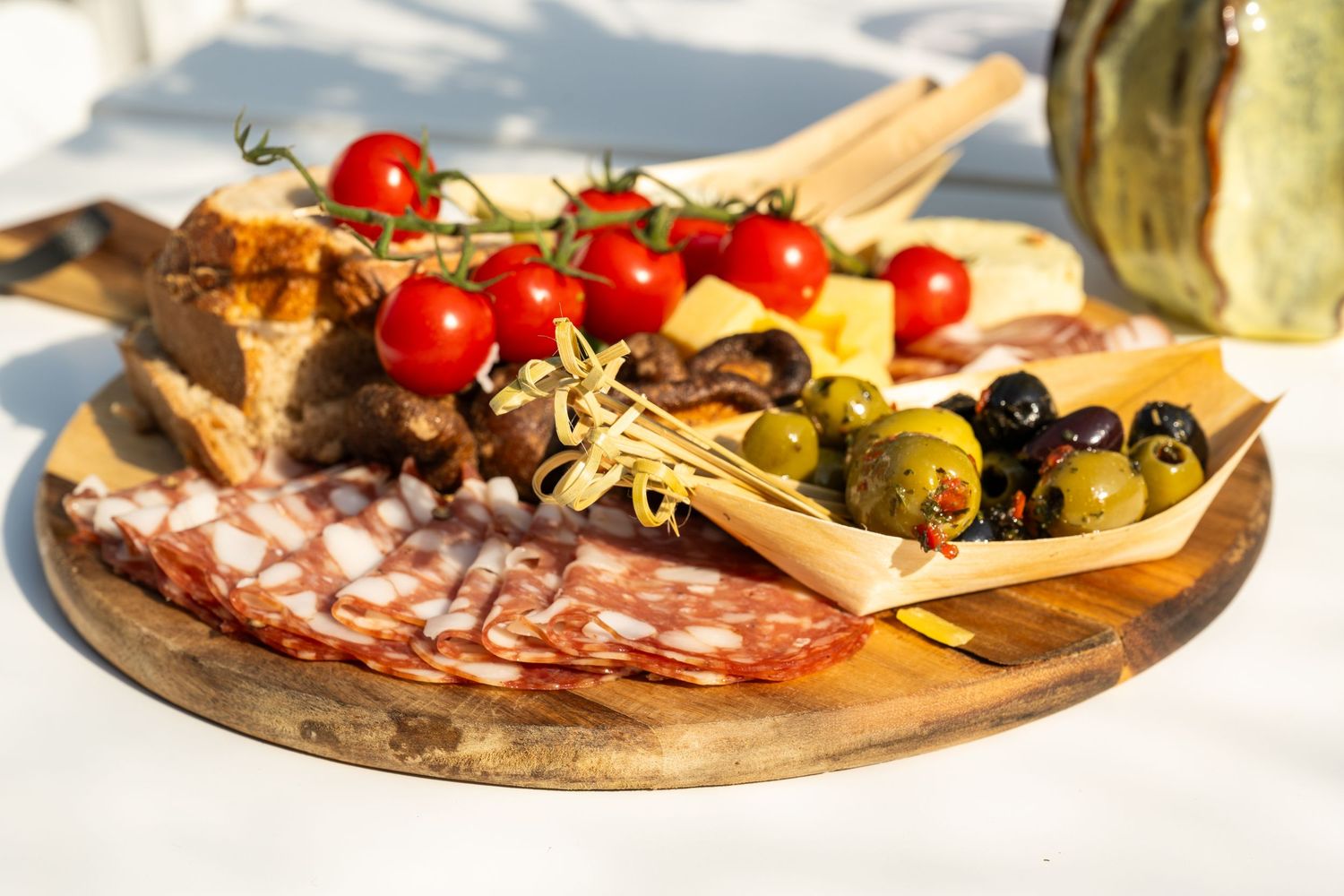 Wooden charcuterie board with assorted meats, tomatoes, and olives arranged in an appetizing display.