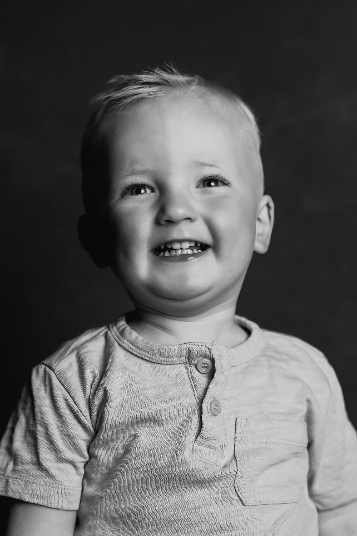 Close-up black and white portrait showing joyful expression in natural lighting.
