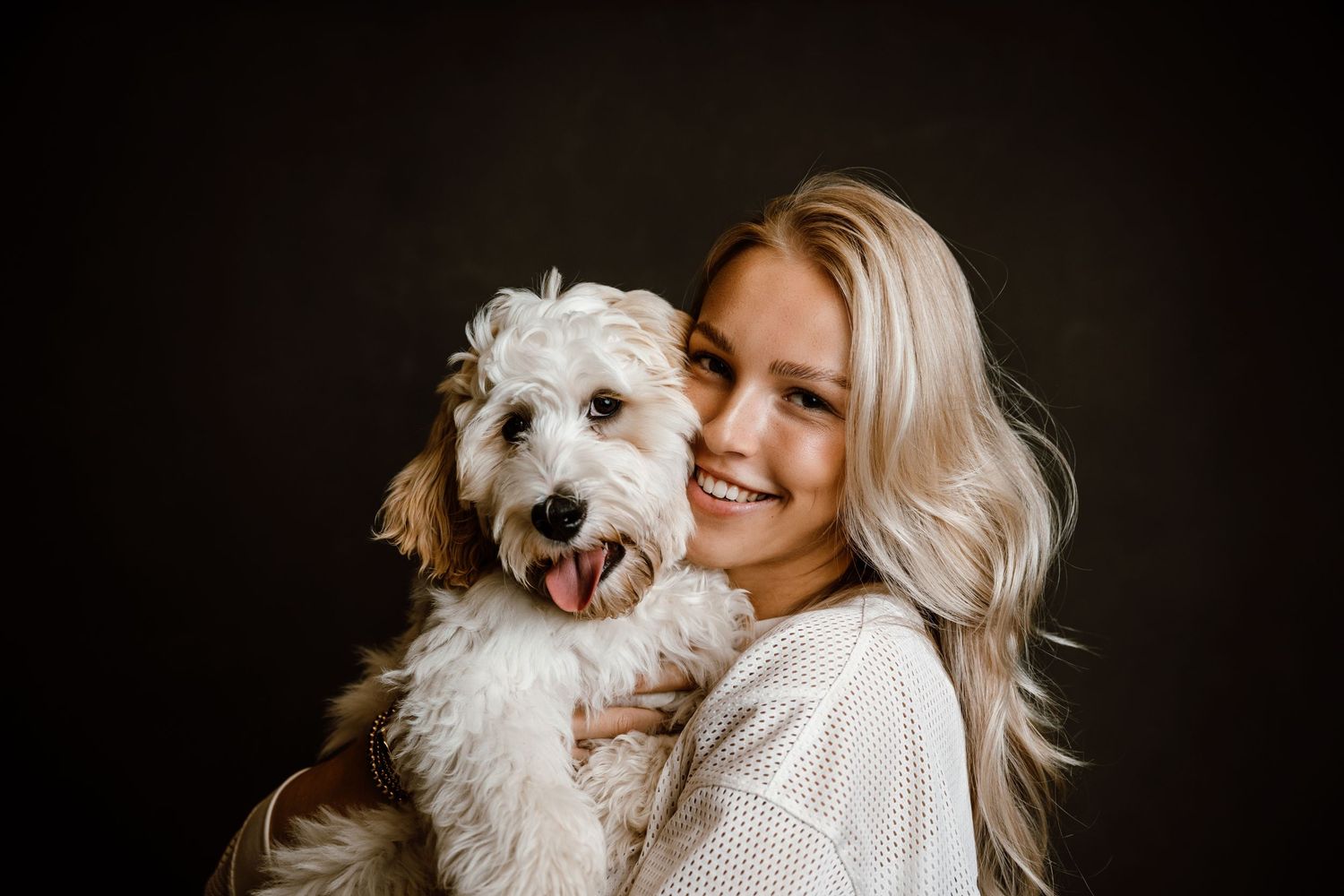White fluffy dog being held and cuddled in a cozy indoor portrait session.