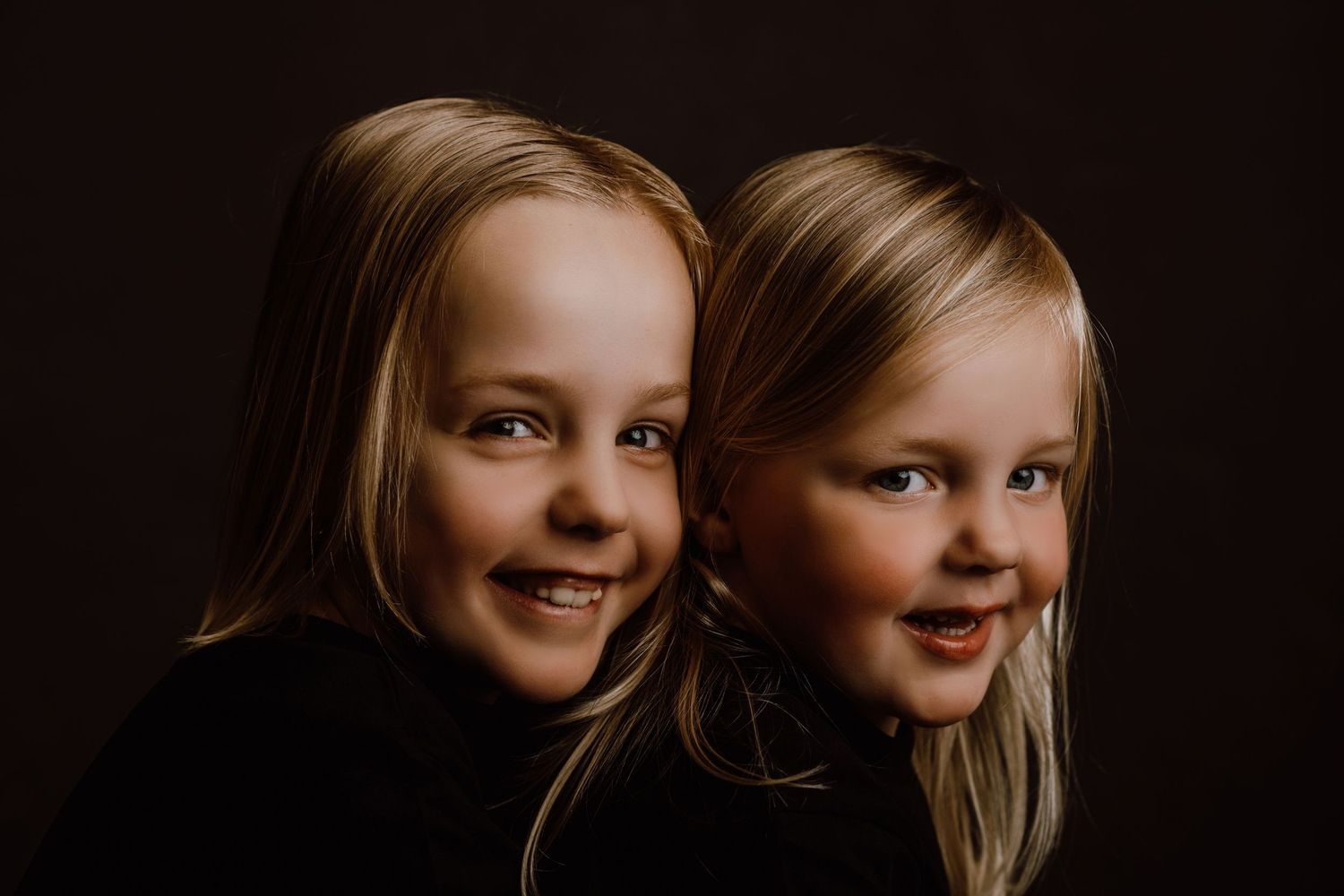 Dramatic studio portraits with dark background showcase joyful expressions.