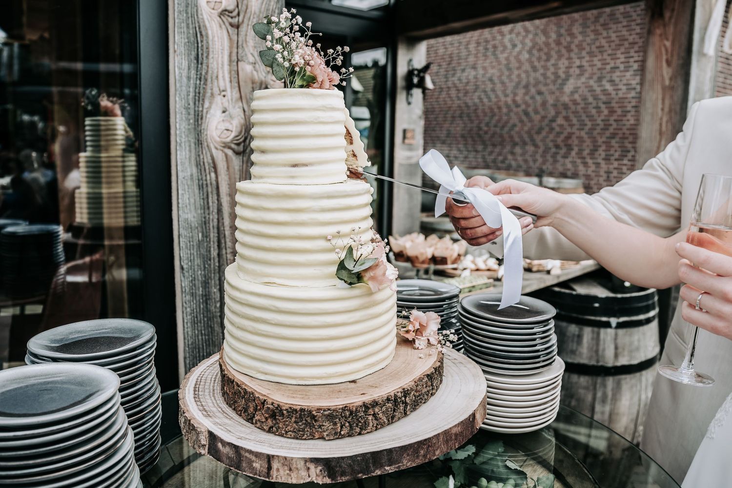 White tiered wedding cake being assembled with textured frosting and decorative details.