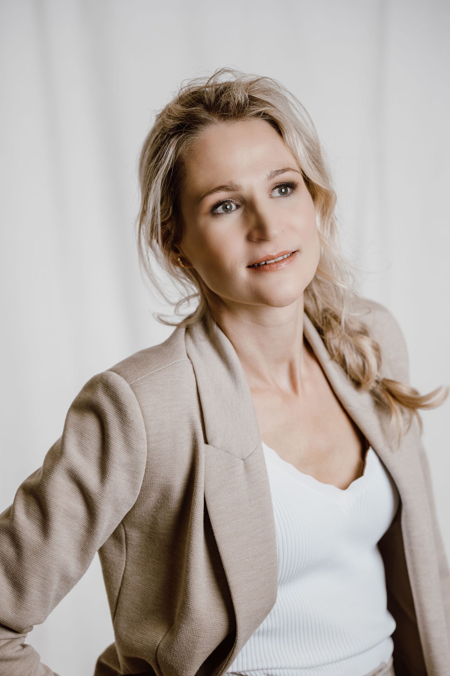Fashion portraits in beige blazer showing dynamic poses against light background.