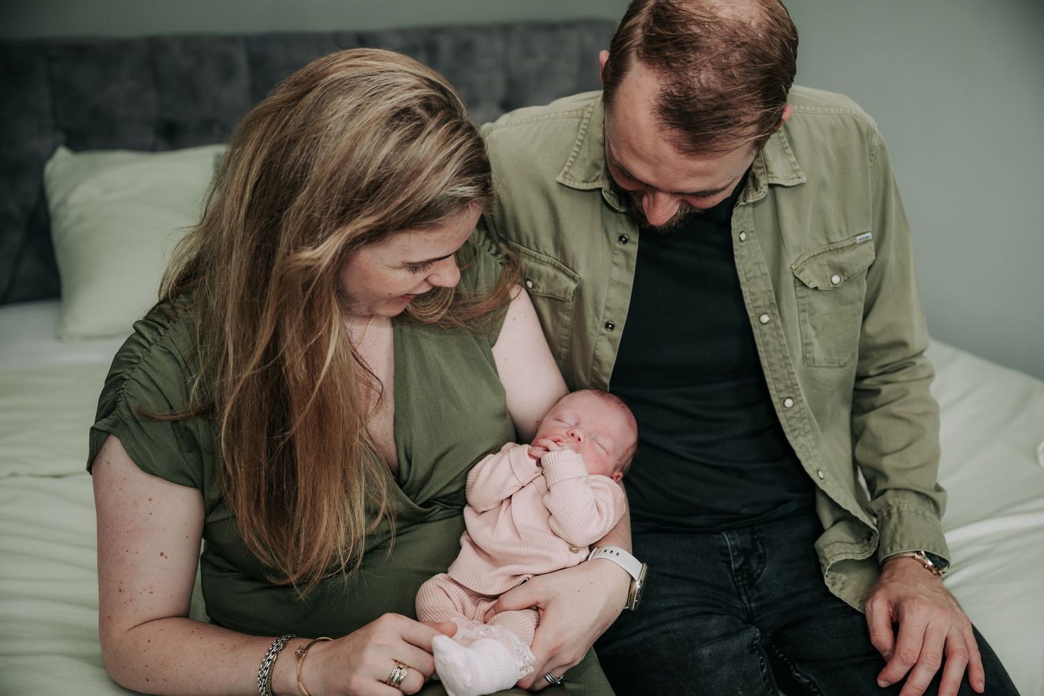 A series of tender moments between parents and their newborn baby in an intimate indoor setting.