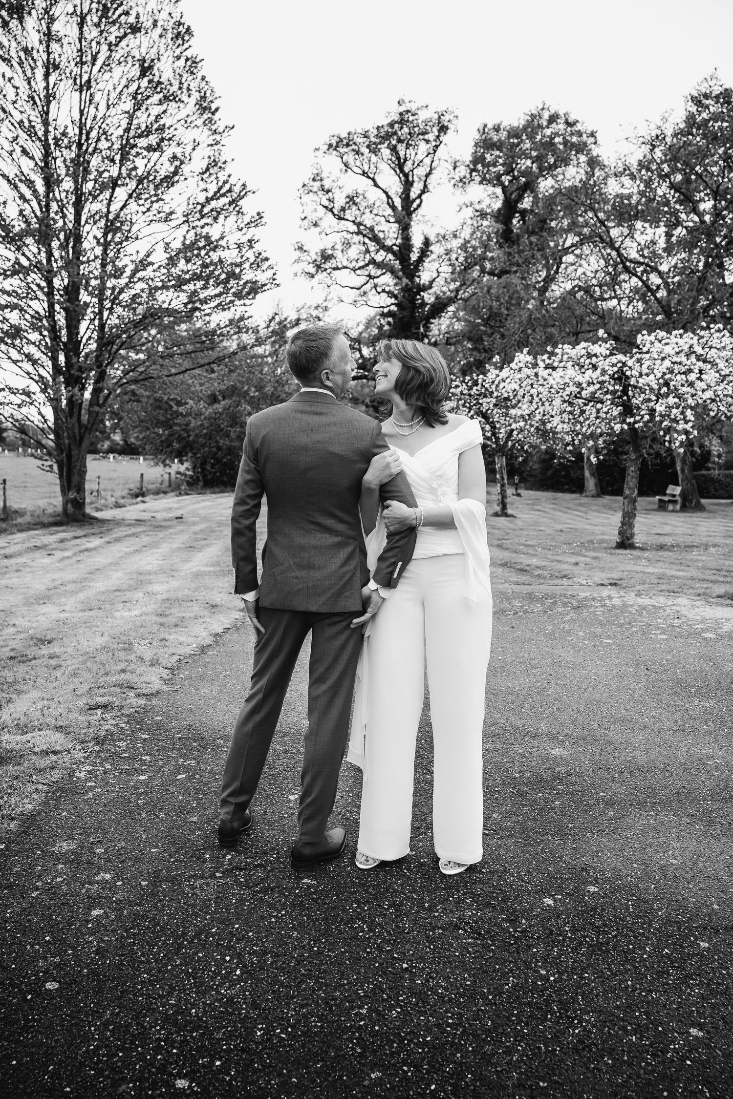 Black and white wedding photography sequence showing couple walking through garden setting.