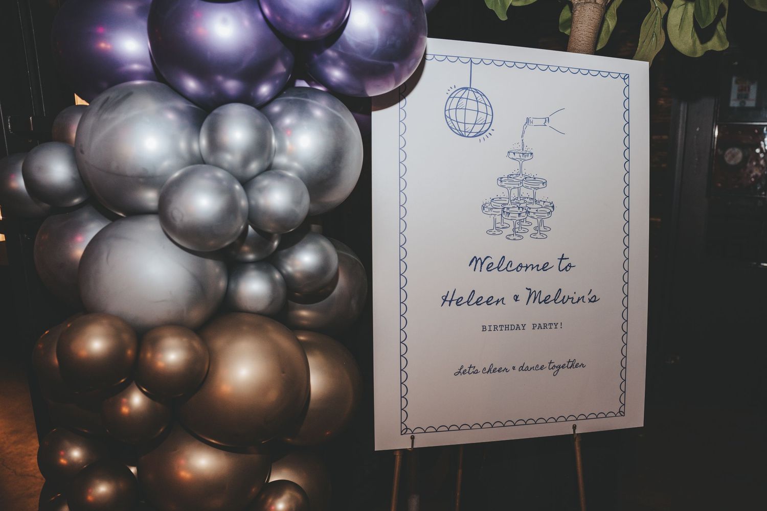 Purple and silver balloon arrangements with welcome signage for an elegant event.