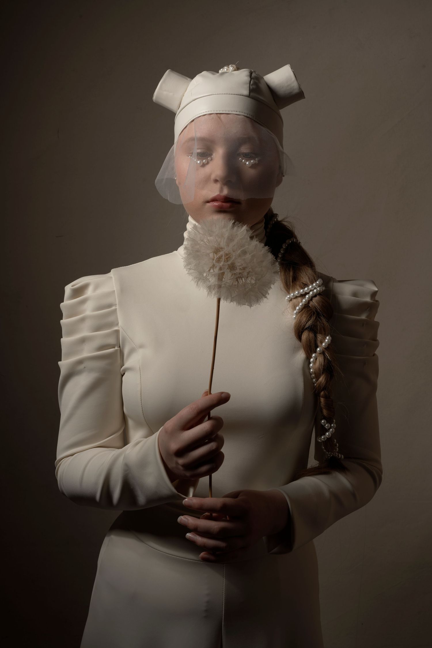 Artistic portrait in cream-colored Victorian-style dress with dramatic studio lighting.