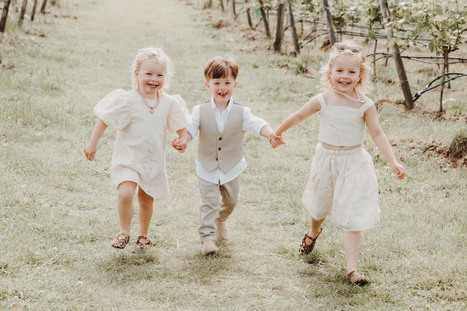 Three children playing and running together in a sunny garden setting.