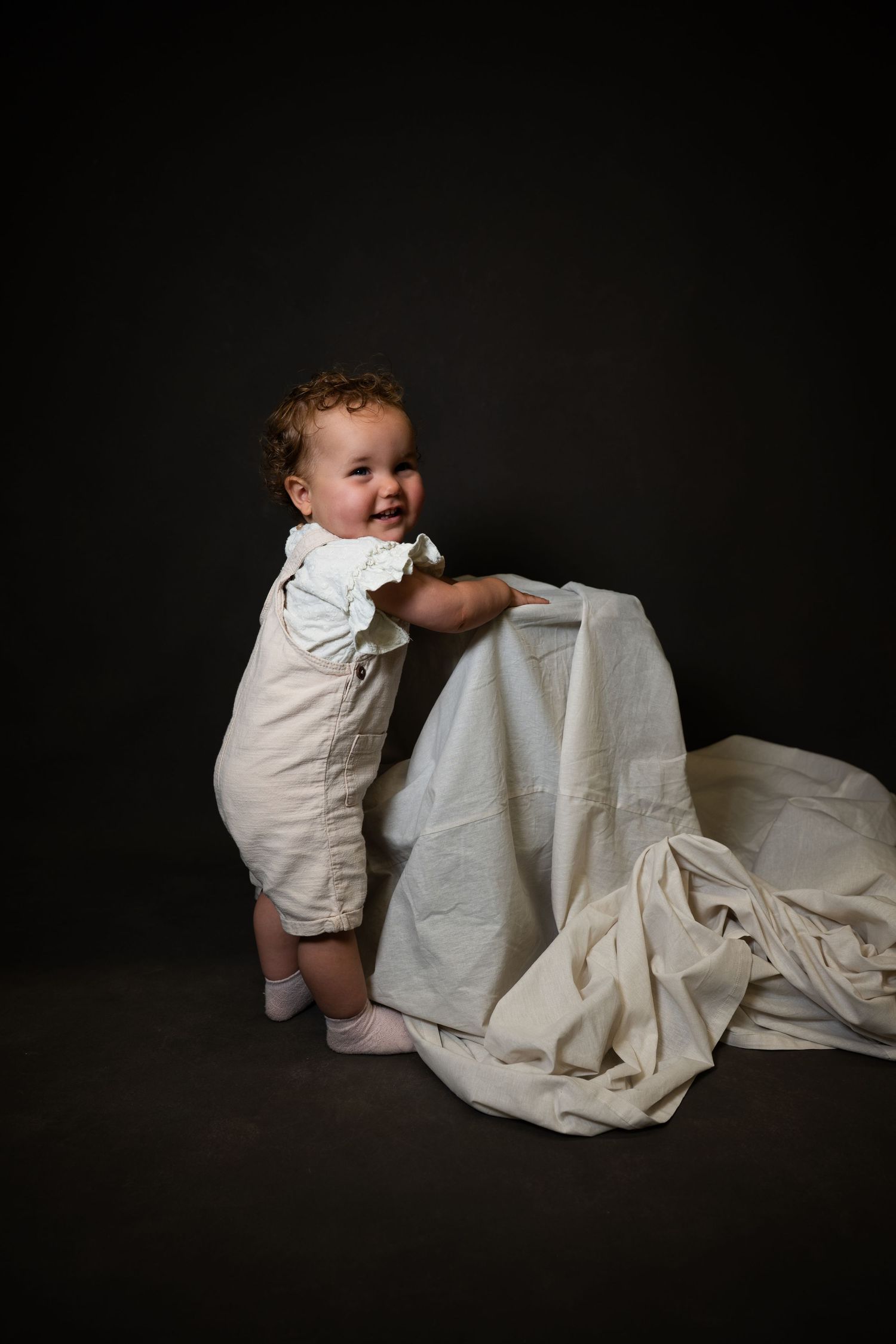 Artistic black and white studio portrait of a baby with flowing fabric.