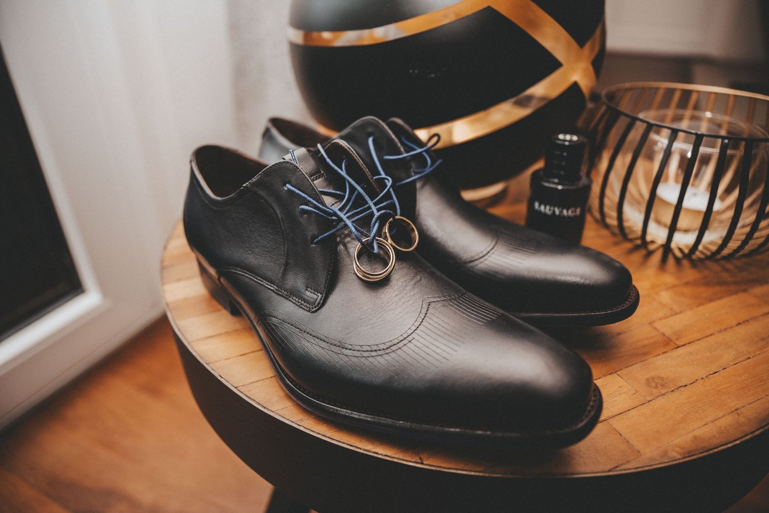 A pair of formal black leather dress shoes on a wooden surface.