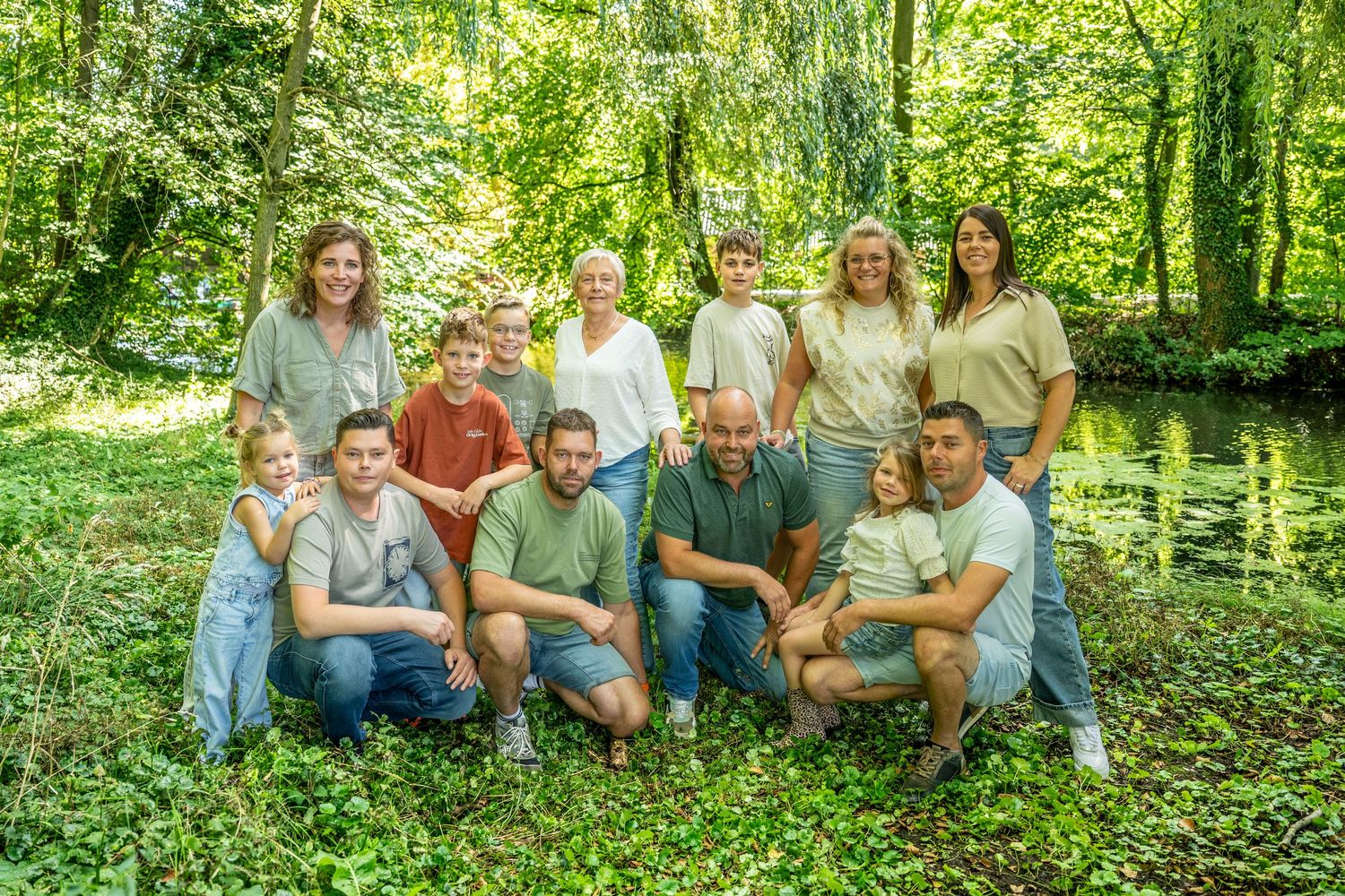 Extended family group photo in lush green forest setting wearing coordinated outfits.