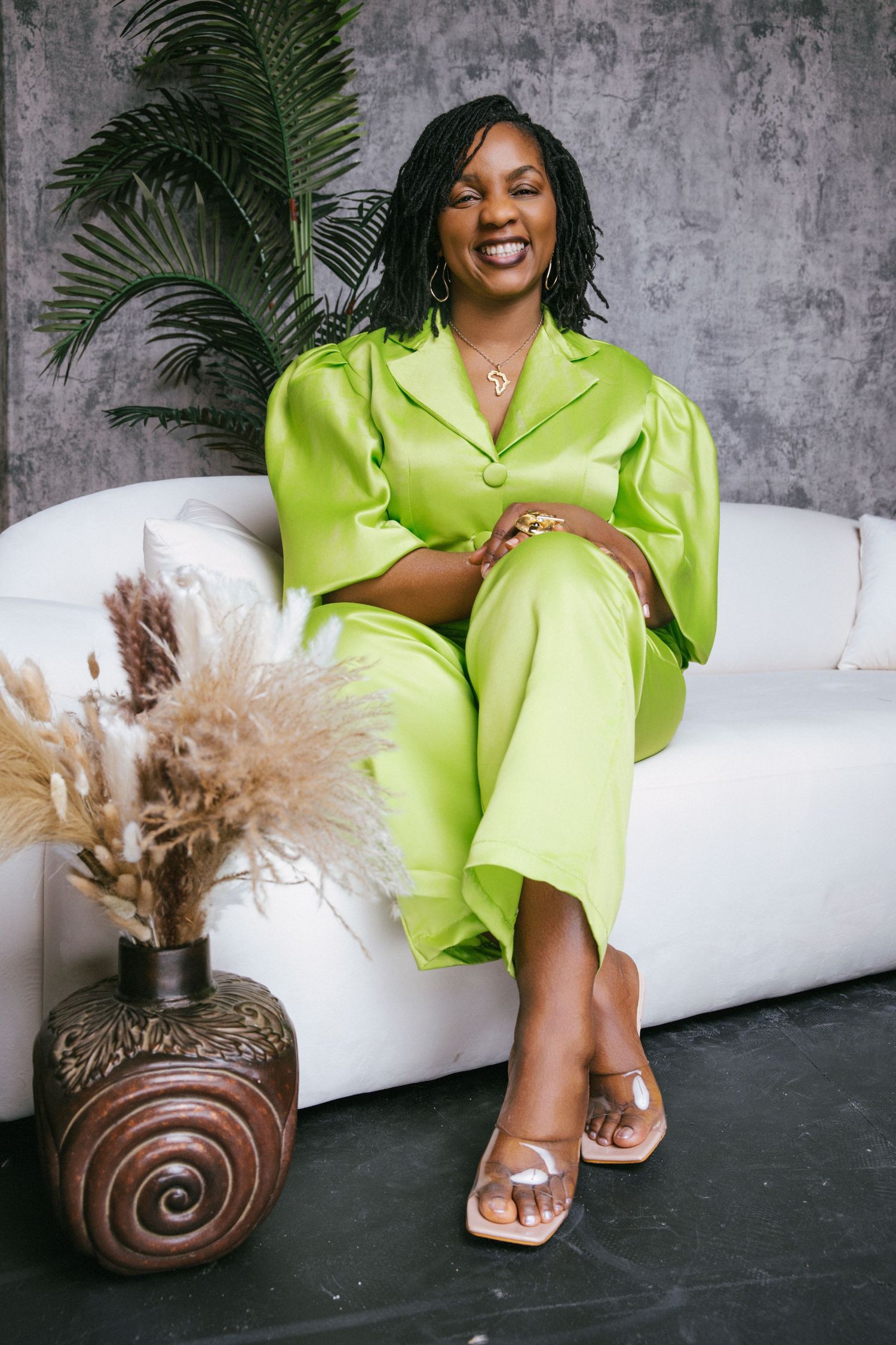 Lifestyle portrait. Dr. Massaley in light green outfit, sitting down in a white loveseat.
