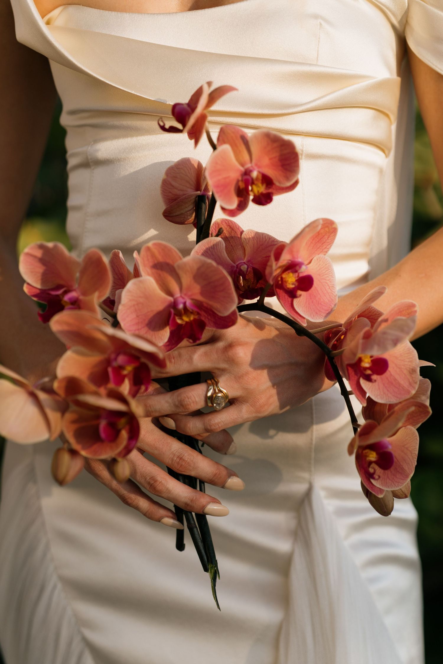 Close-up of pink orchids adorning a white wedding dress.