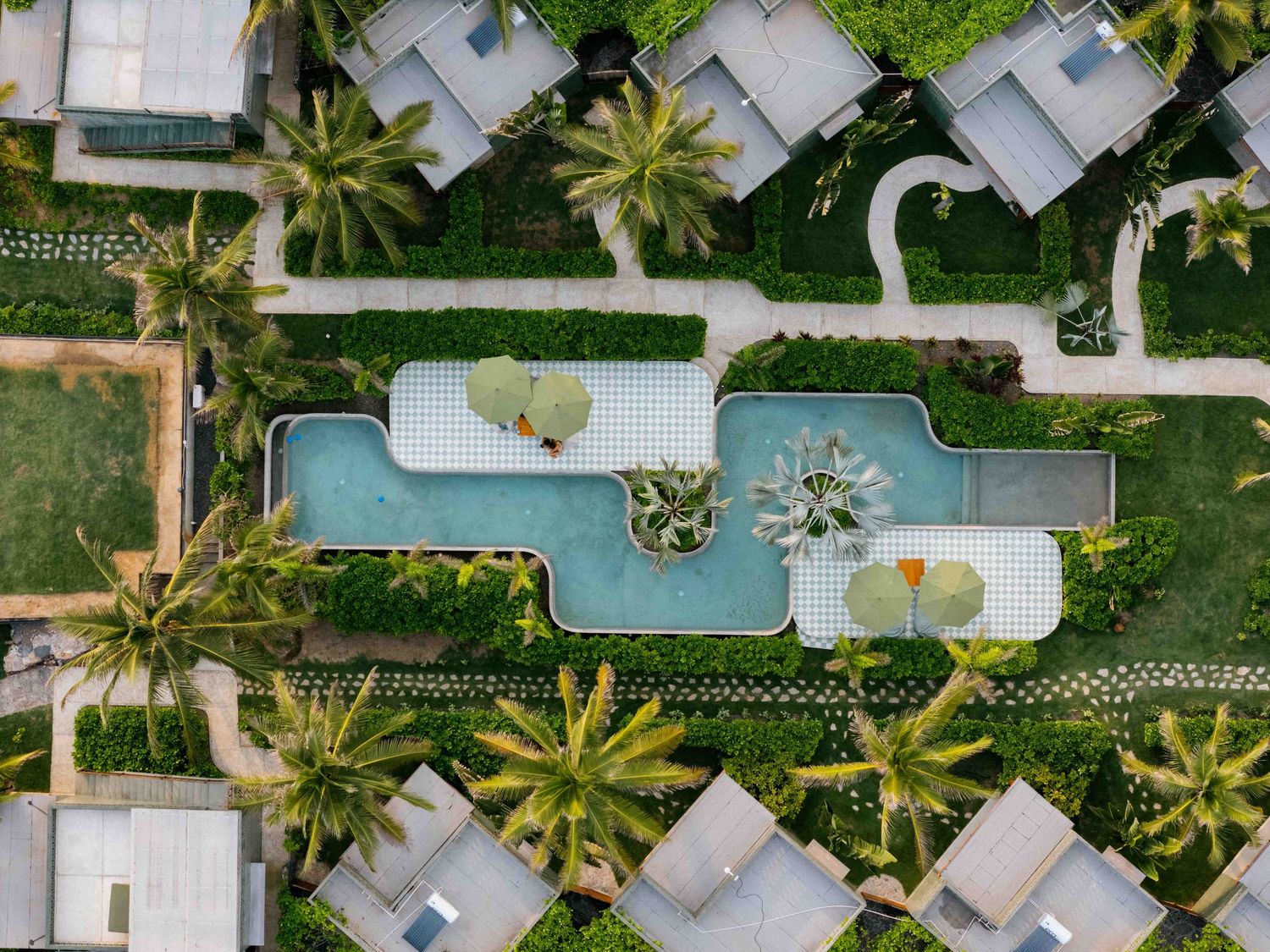 Aerial view of luxury beachfront homes with swimming pools and palm trees along a tropical coastline.