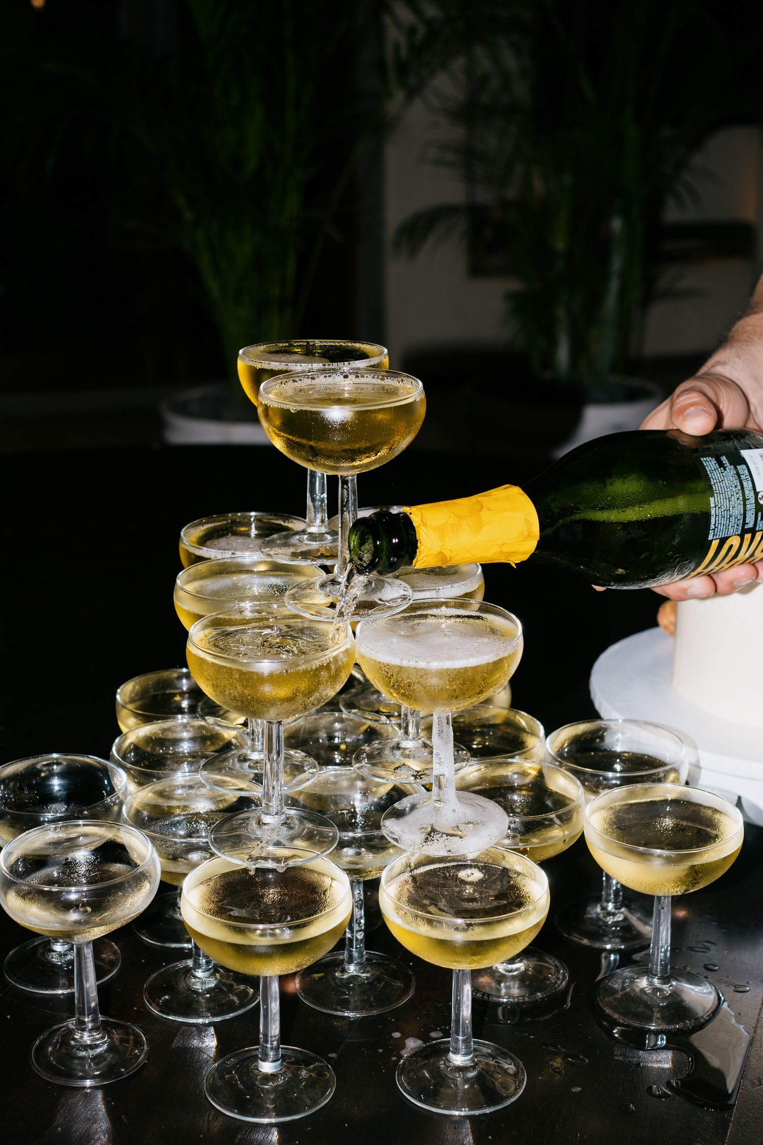 Champagne tower being filled with sparkling wine at an elegant event.