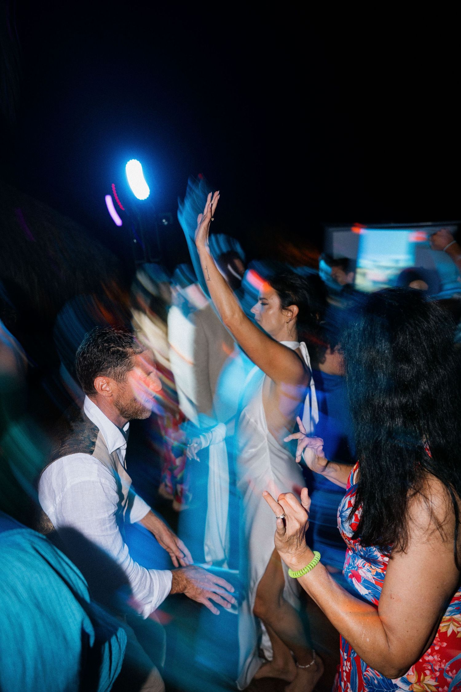 Energetic dance party scene at wedding reception with blue lighting and motion blur effects.