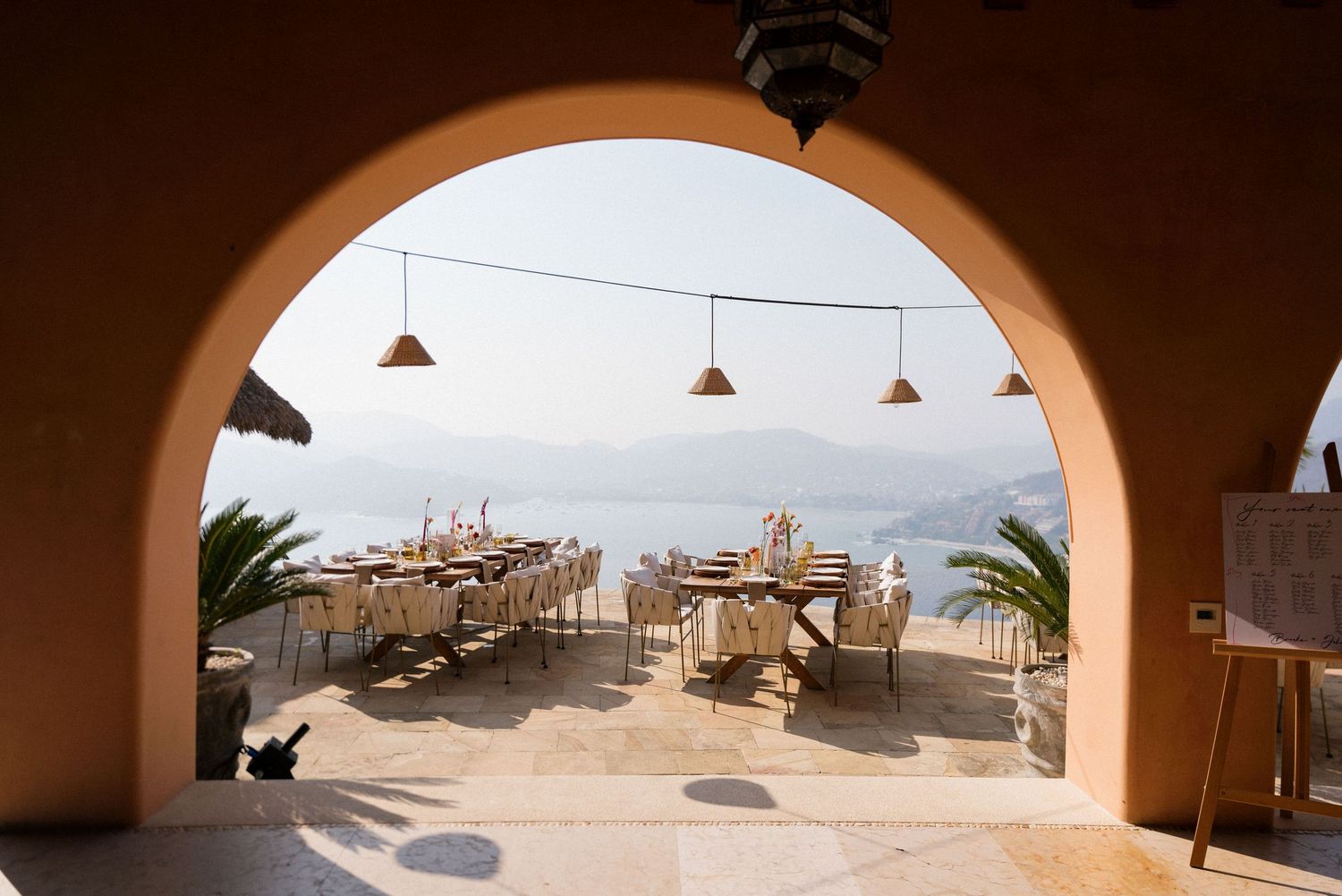 View of a beach resort through arched terrace openings at sunset.