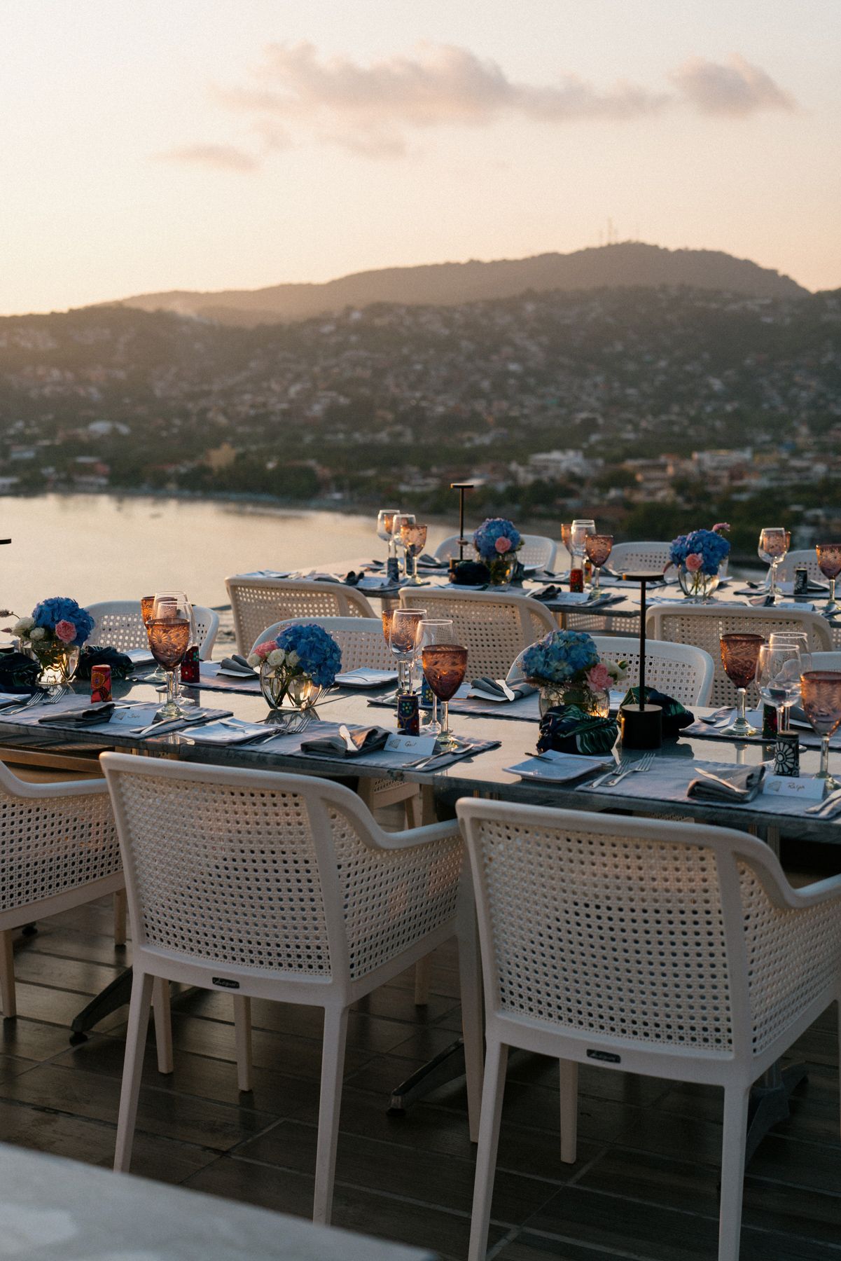 Sunset wedding reception table decorated with blue and copper details overlooking a coastal vista.