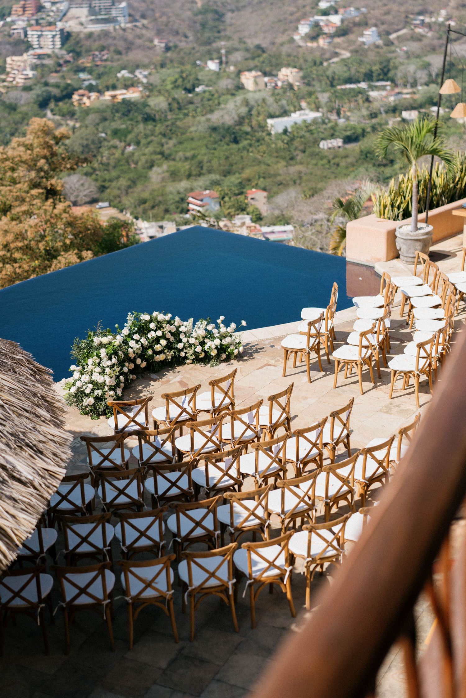 Rustic wooden chairs arranged in rows on a hillside overlooking a scenic coastal view.