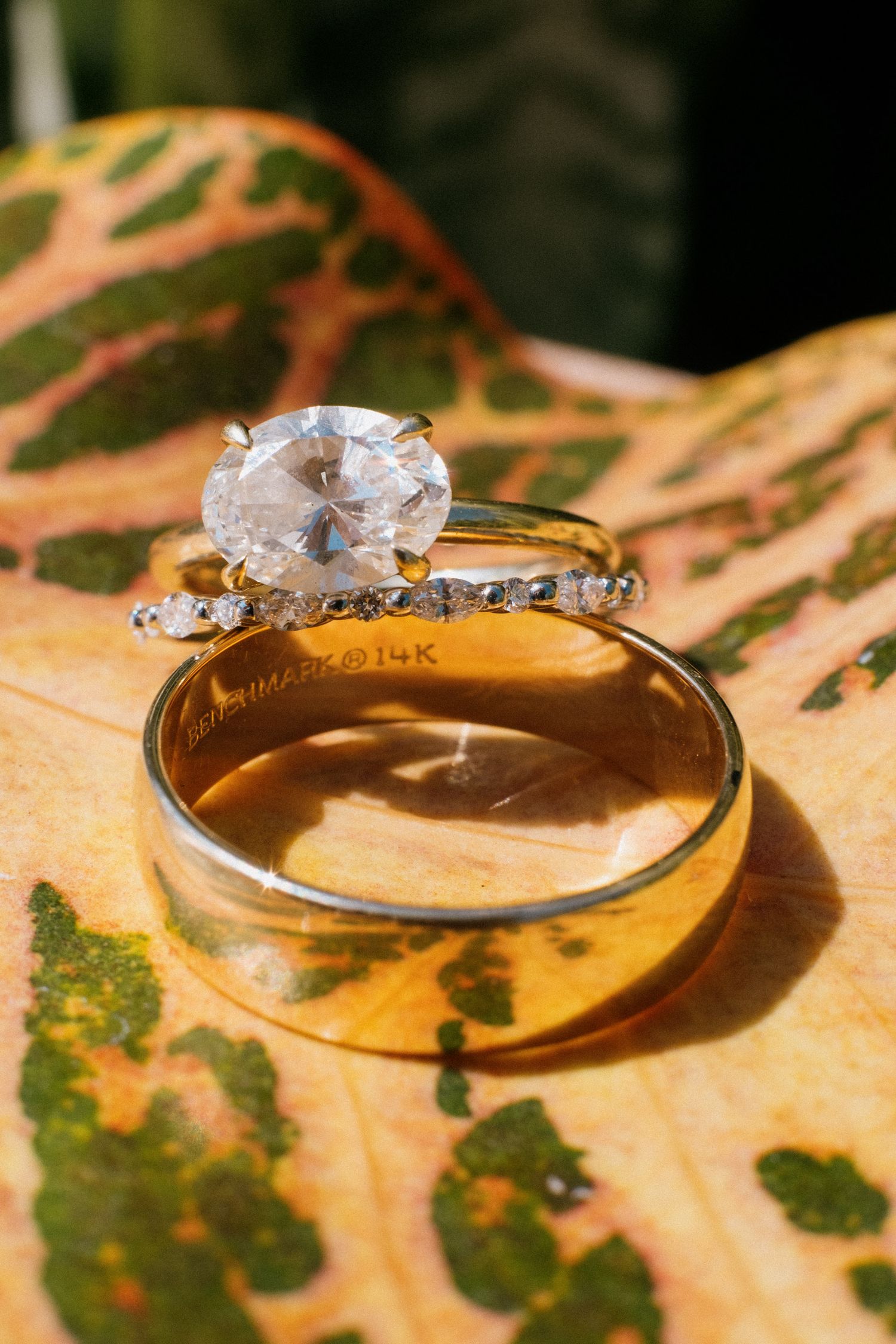 Diamond engagement ring and wedding band photographed on autumn leaf with detailed vein patterns.