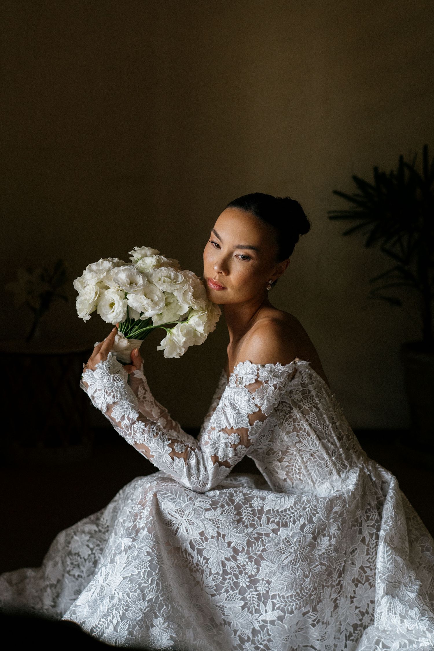 Elegant bridal portrait with white flowers in romantic lace gown.