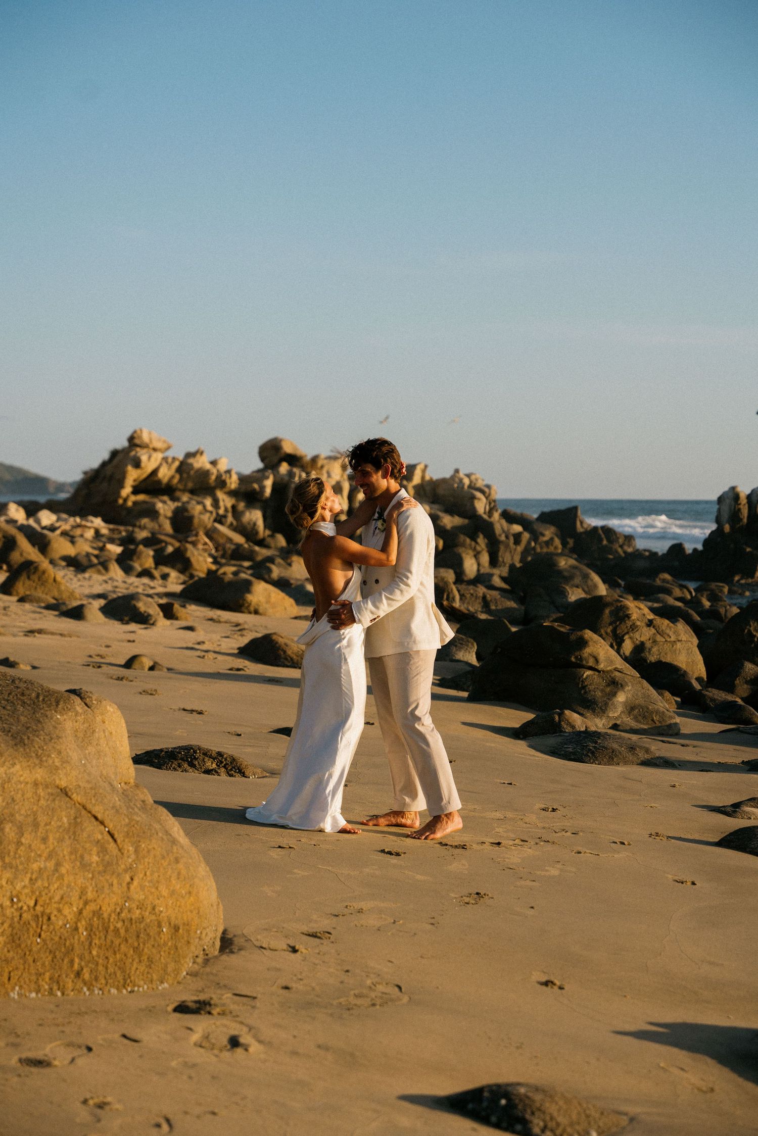 A romantic beach moment among rocky coastal formations at sunset.