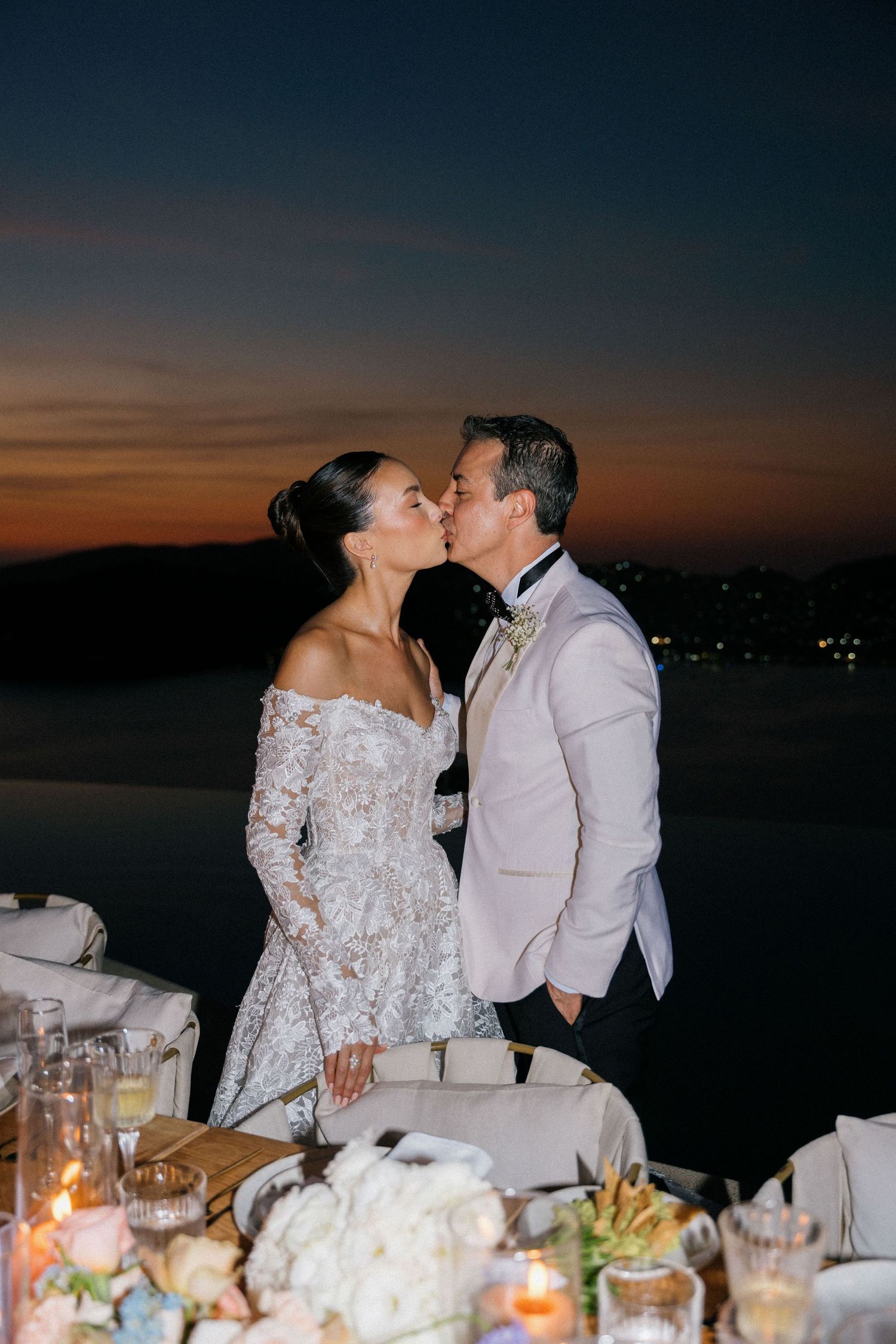 Romantic sunset reception dinner with table settings and candlelight by the ocean.