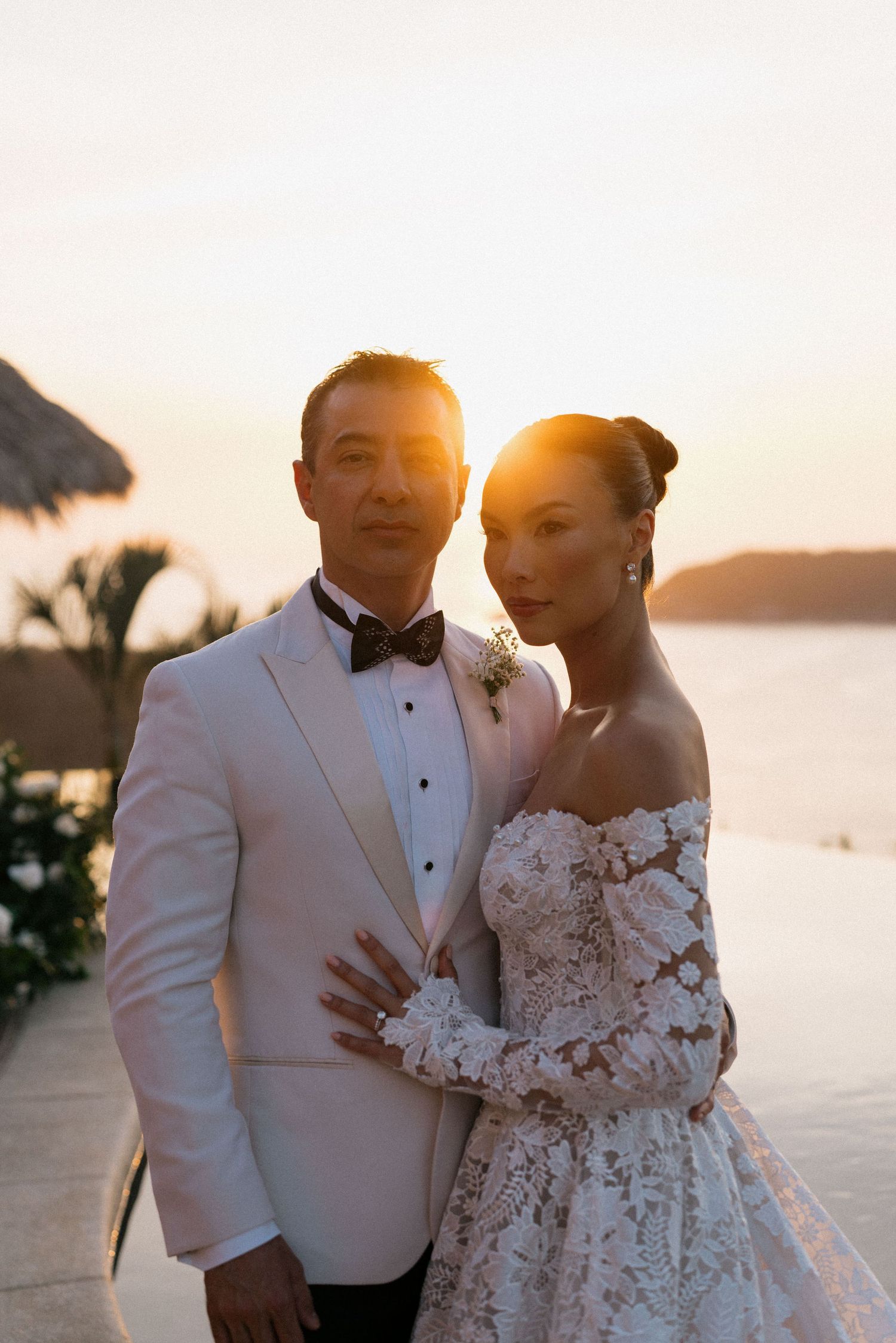 Elegant couple poses during golden hour with ocean vista in the background.