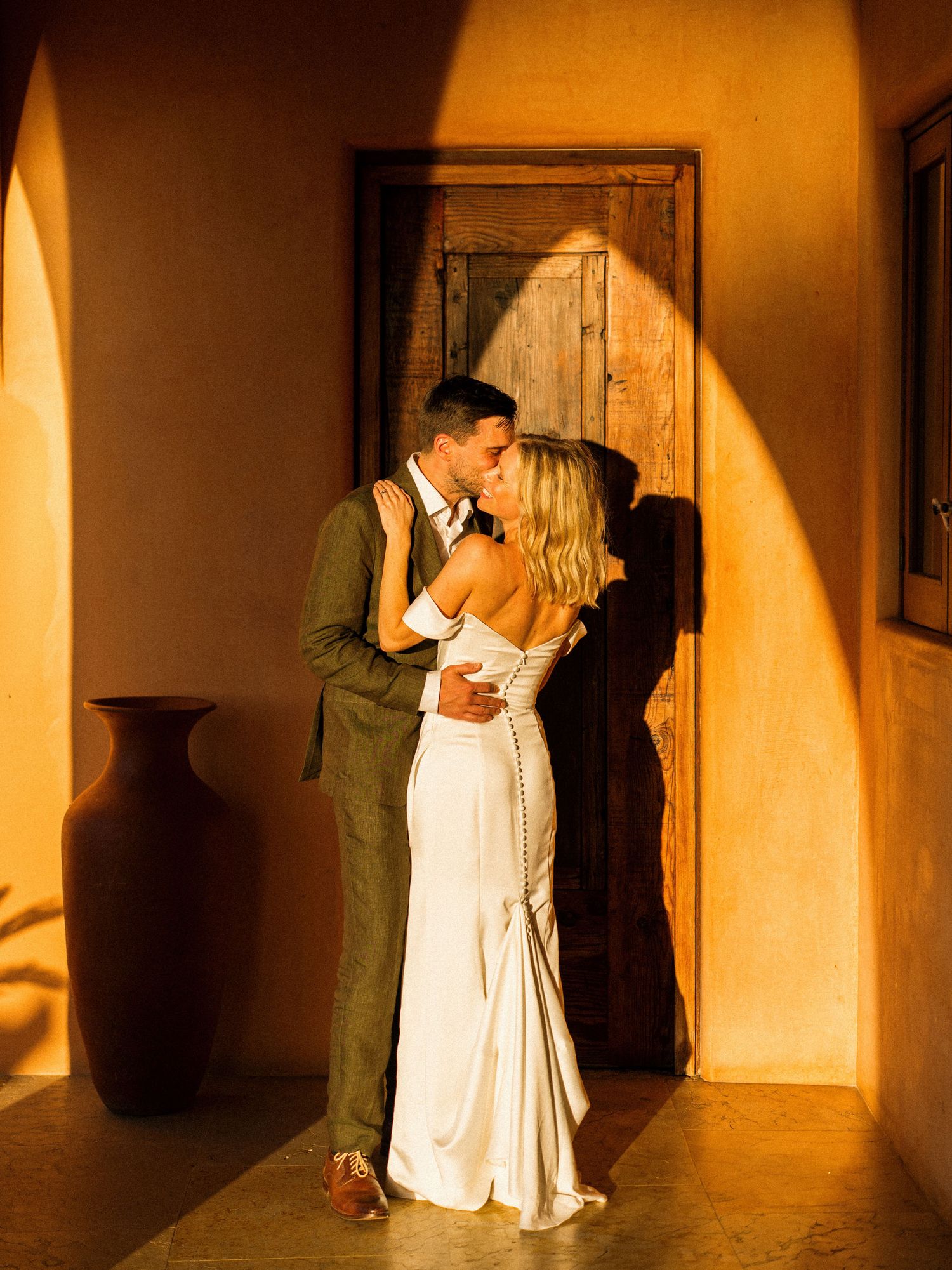 Intimate moment in a warmly lit hallway with dramatic shadows and architecture.