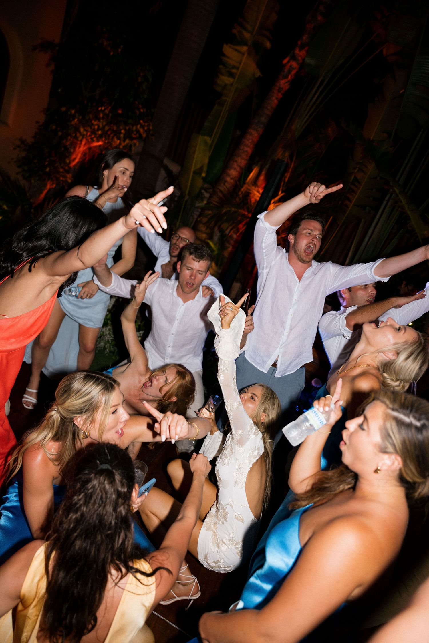 Energetic dance party with guests celebrating on crowded dance floor.