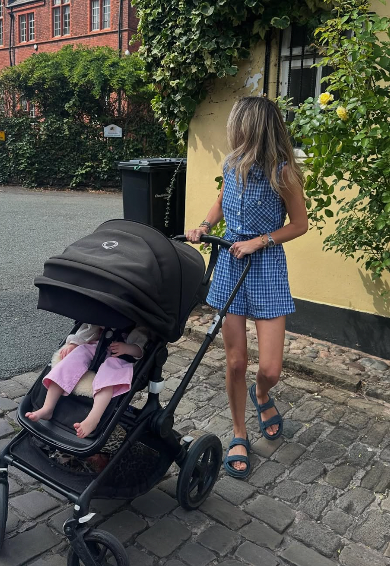 A black stroller is shown from different angles on a cobblestone path next to greenery and a yellow wall.