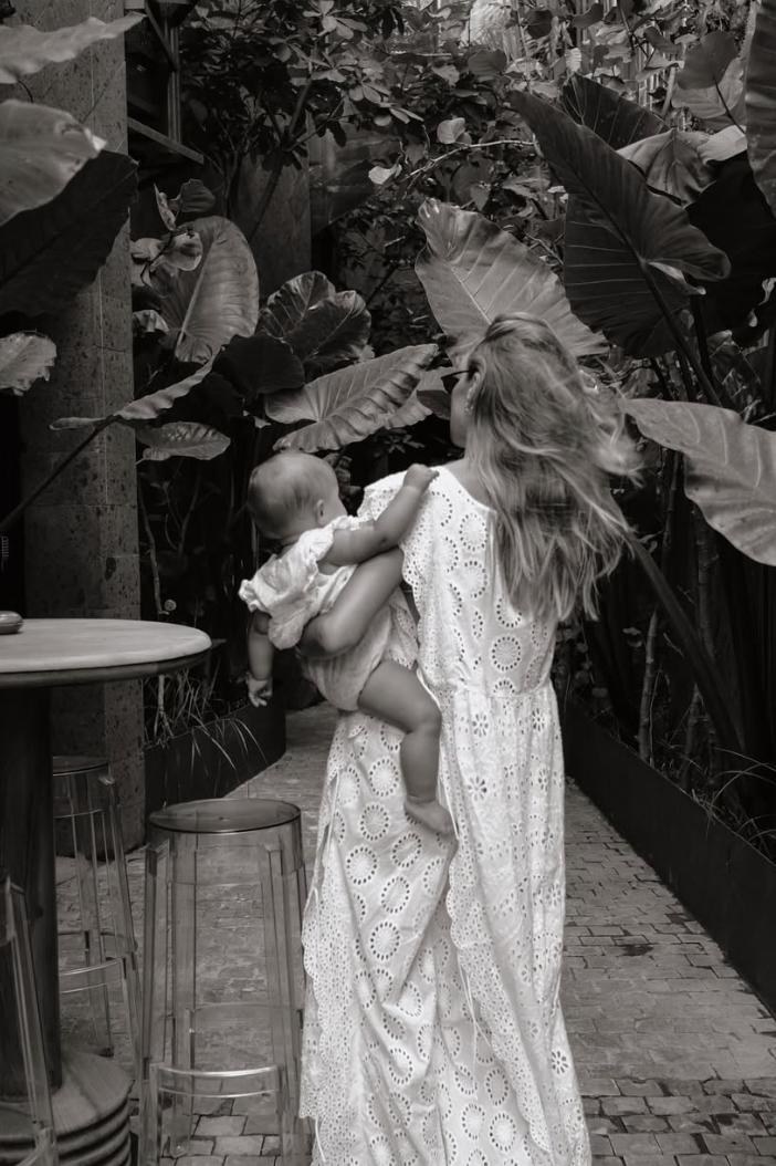 A tender black and white moment captured in a garden setting with lush tropical leaves in the background.