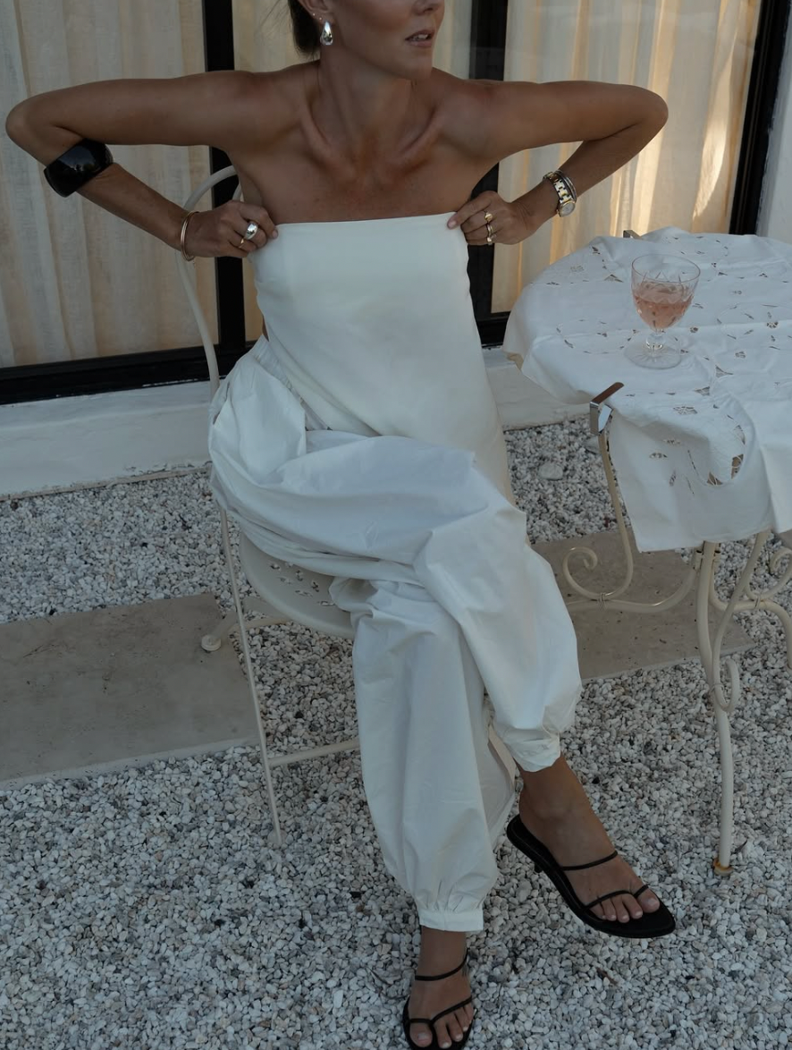 A series of five photos showing white pants and black strappy sandals against a speckled floor background.