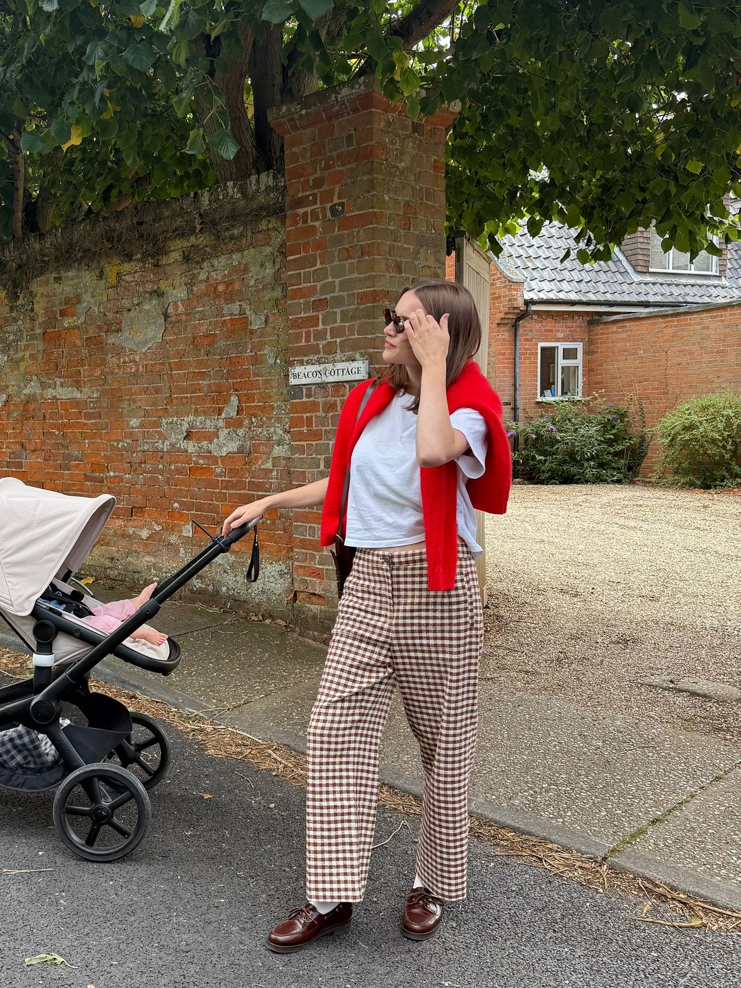 A series of photos showing someone in brown plaid pants and red scarf walking and interacting with a baby stroller outdoors.