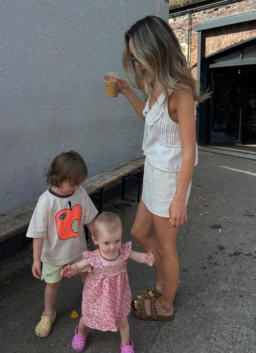 A toddler in pink and a caregiver walk by a brick wall, with multiple photos showing them in different poses.