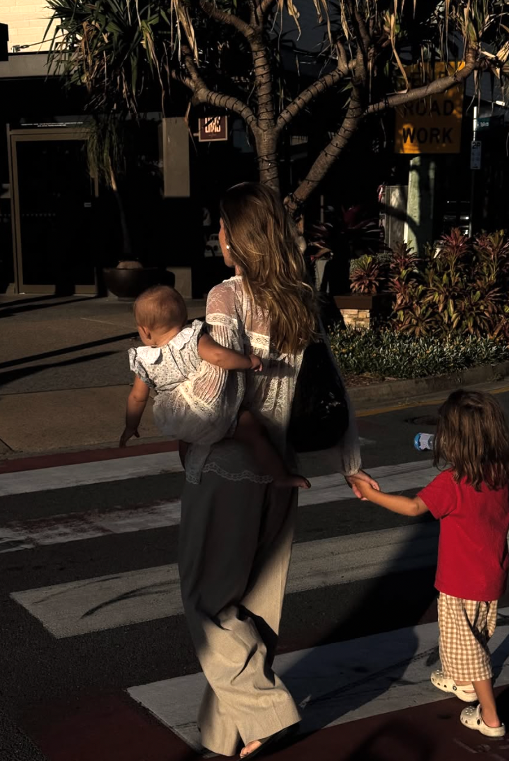 People walking on a sidewalk casting long shadows during golden hour while using mobile phones.