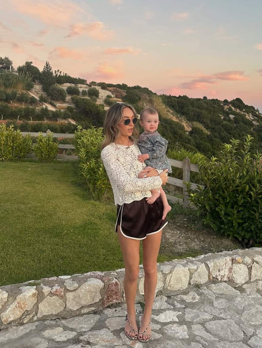 A sunset photoshoot on a stone wall with scenic coastal views in the background.