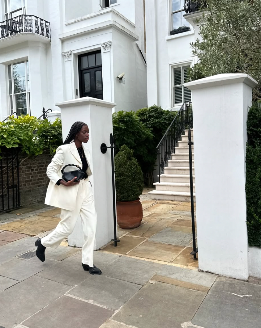 A sequence of photos showing someone in a white outfit performing a silly walk inspired by Monty Python outside a building.
