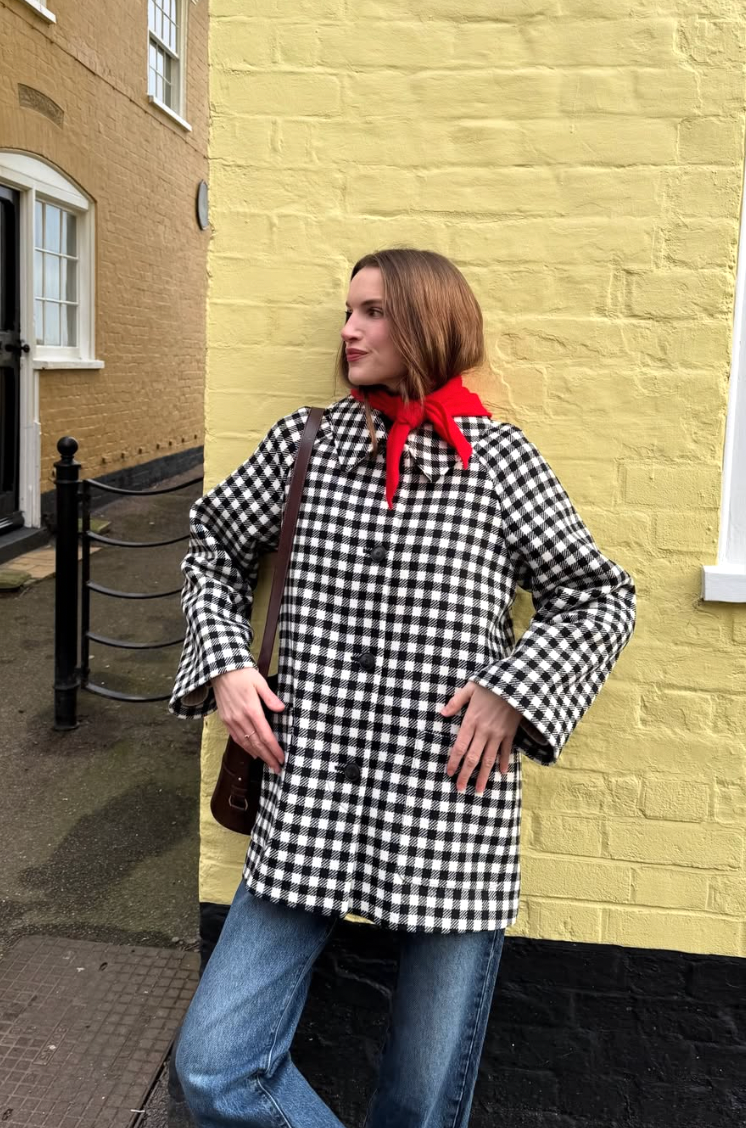 A series of fashion poses showing a black and white gingham jacket with red accent against a yellow brick wall.
