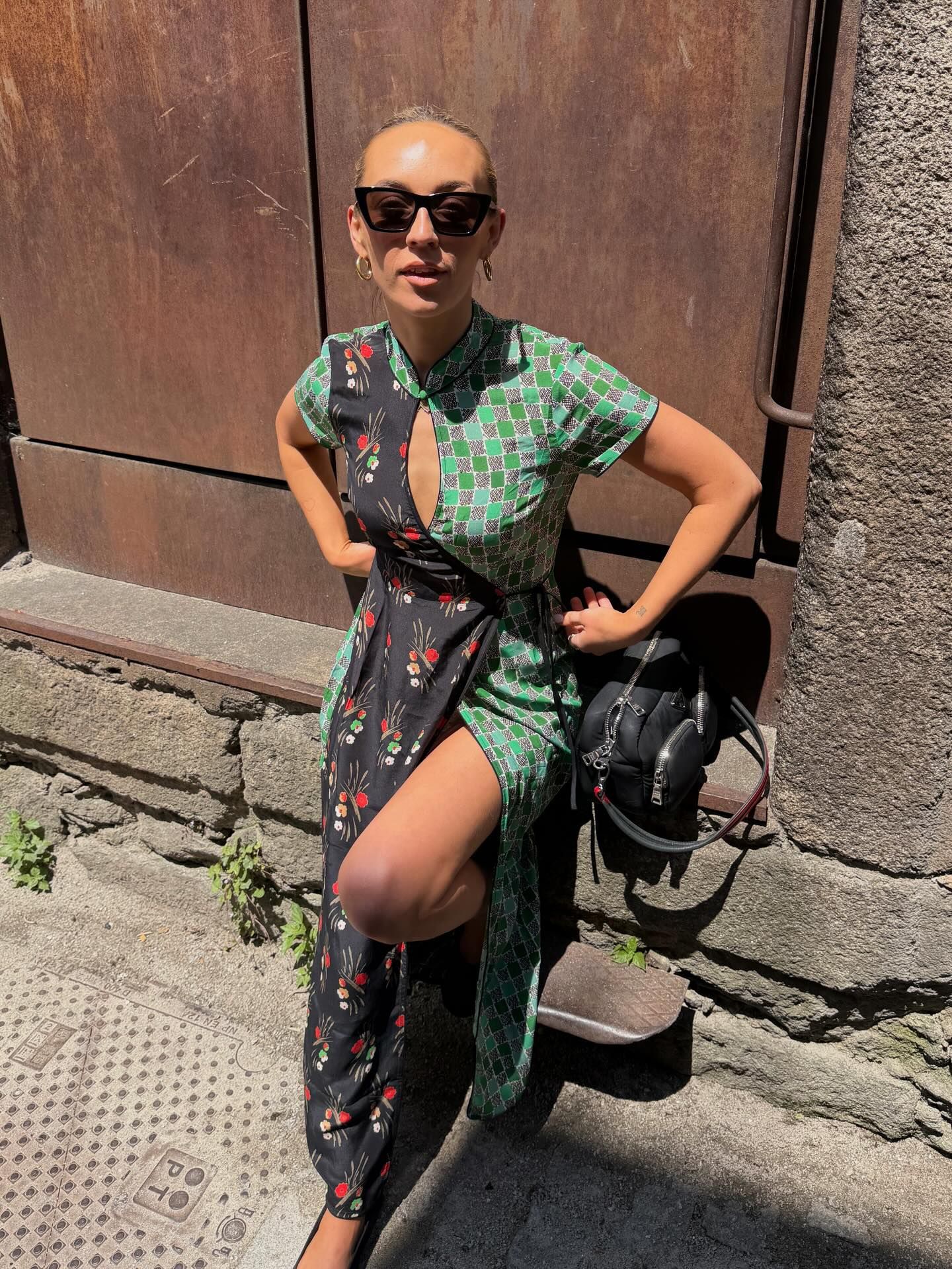 Woman wearing green floral print midi dress with keyhole neckline and thigh slit, posing outdoors in cat-eye sunglasses.
