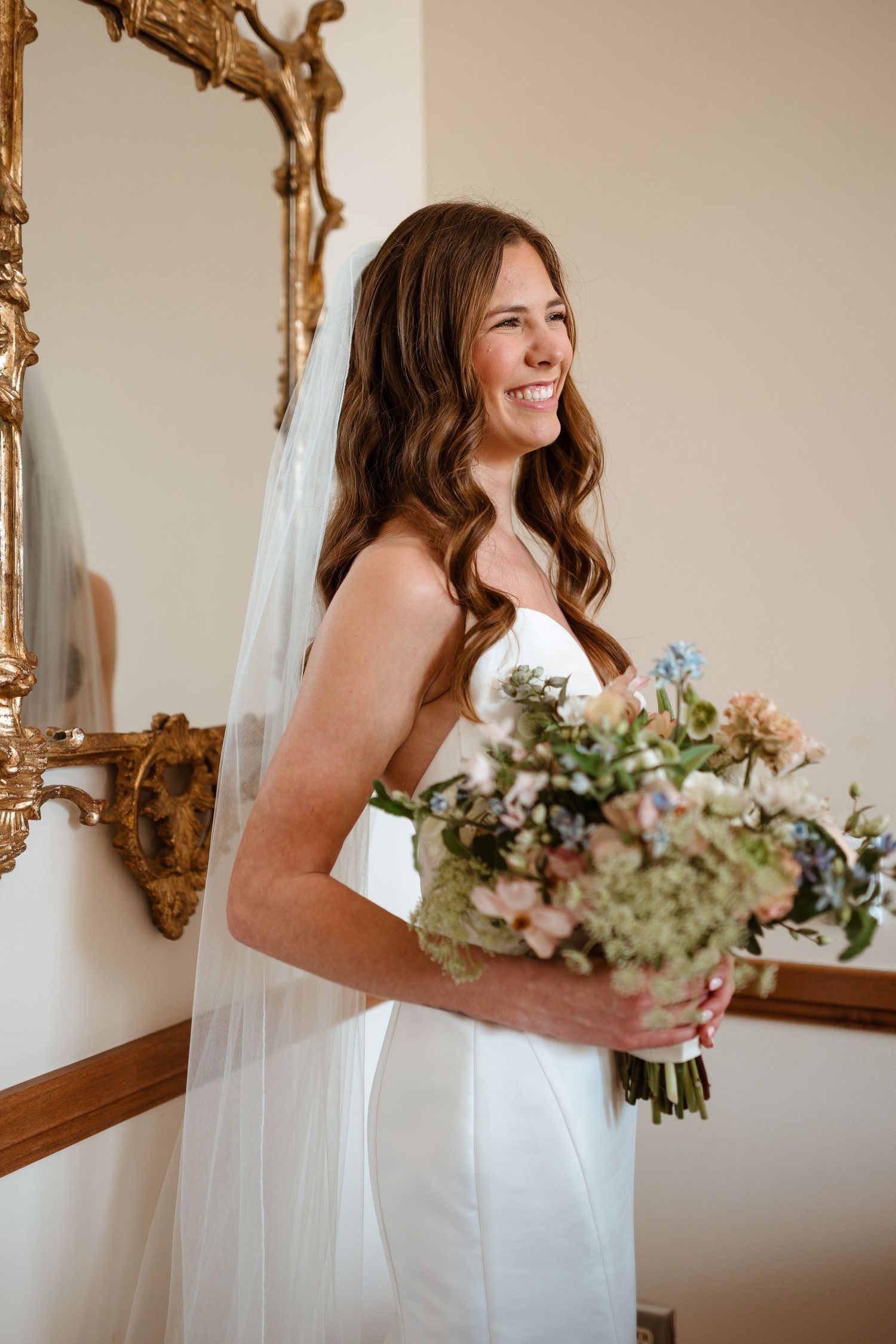 Bride smiling while holding bouquet.