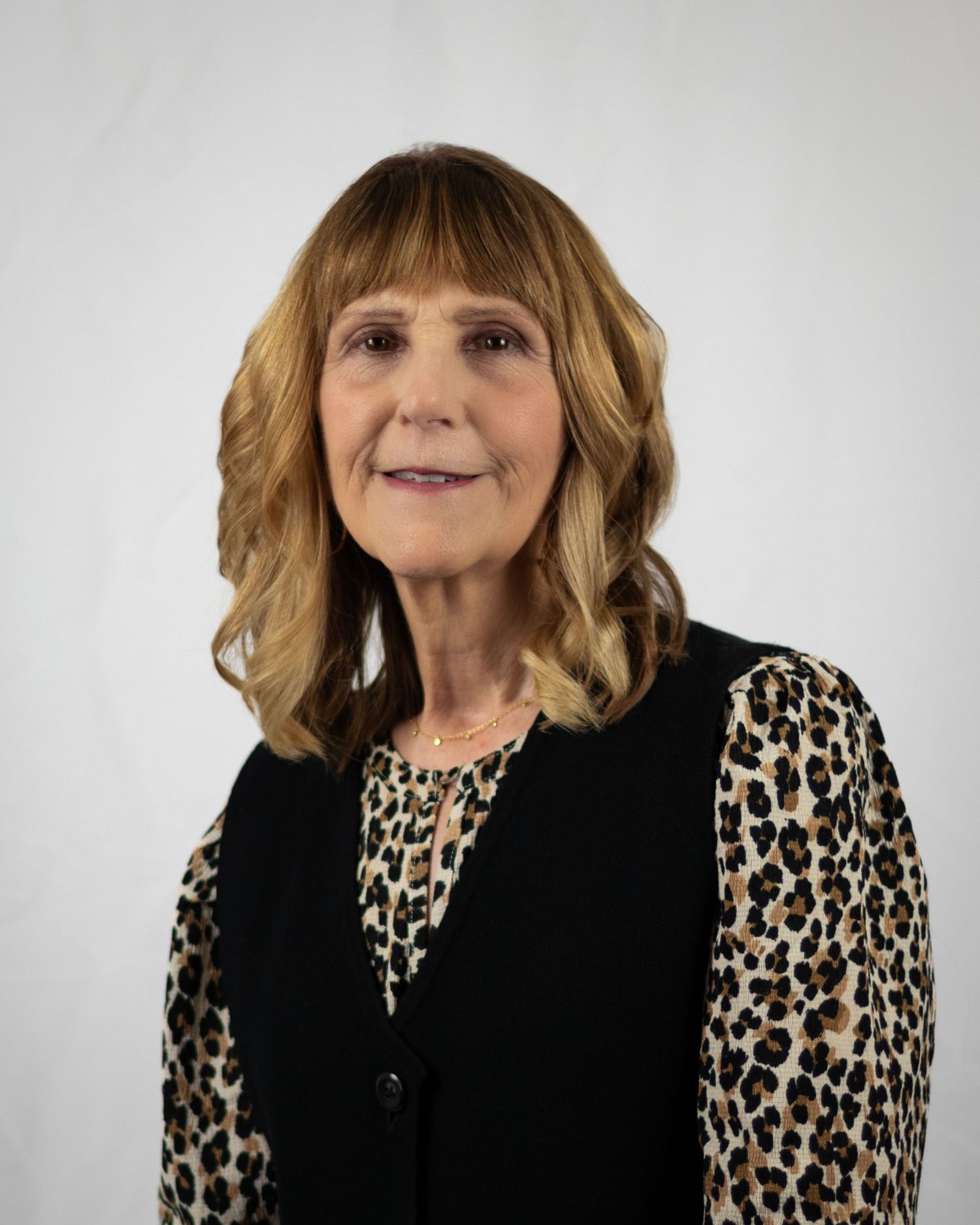 Senior woman in a blazer headshot againt a white backdrop.