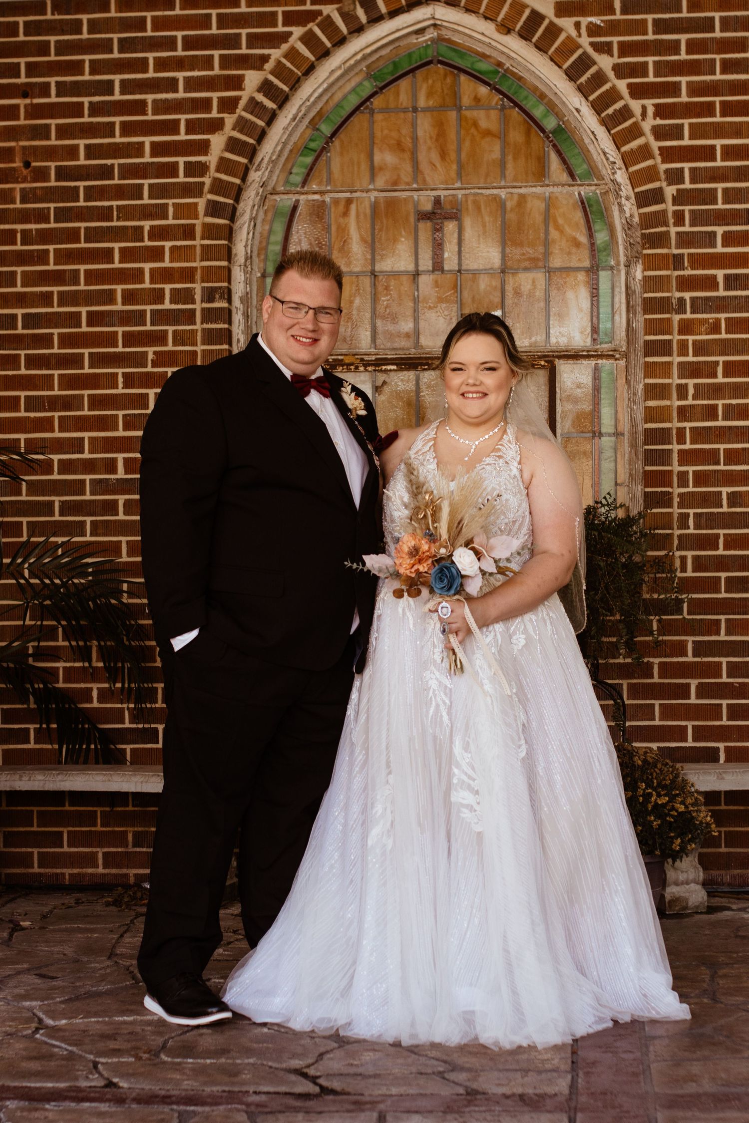 Picture of a couple on their wedding day against a brick wall.